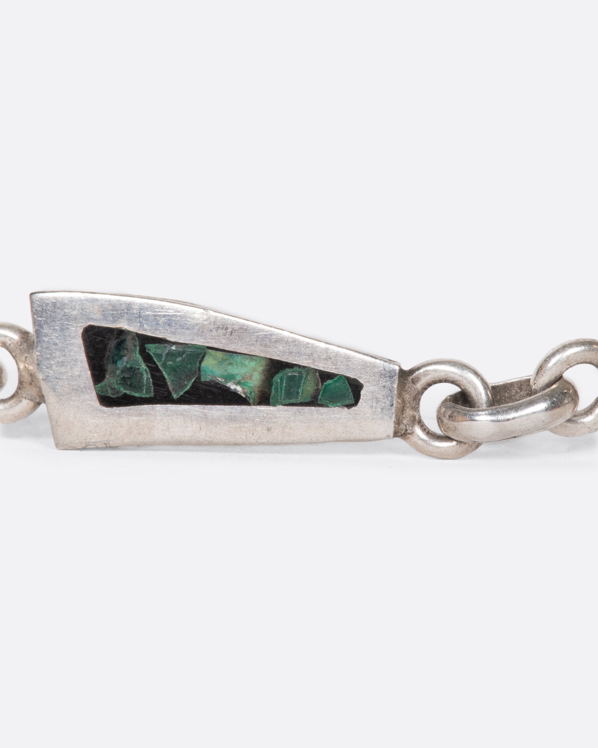 A sterling silver chain bracelet with long, trapezoidal links, lined with malachite inlay, shown close up.
