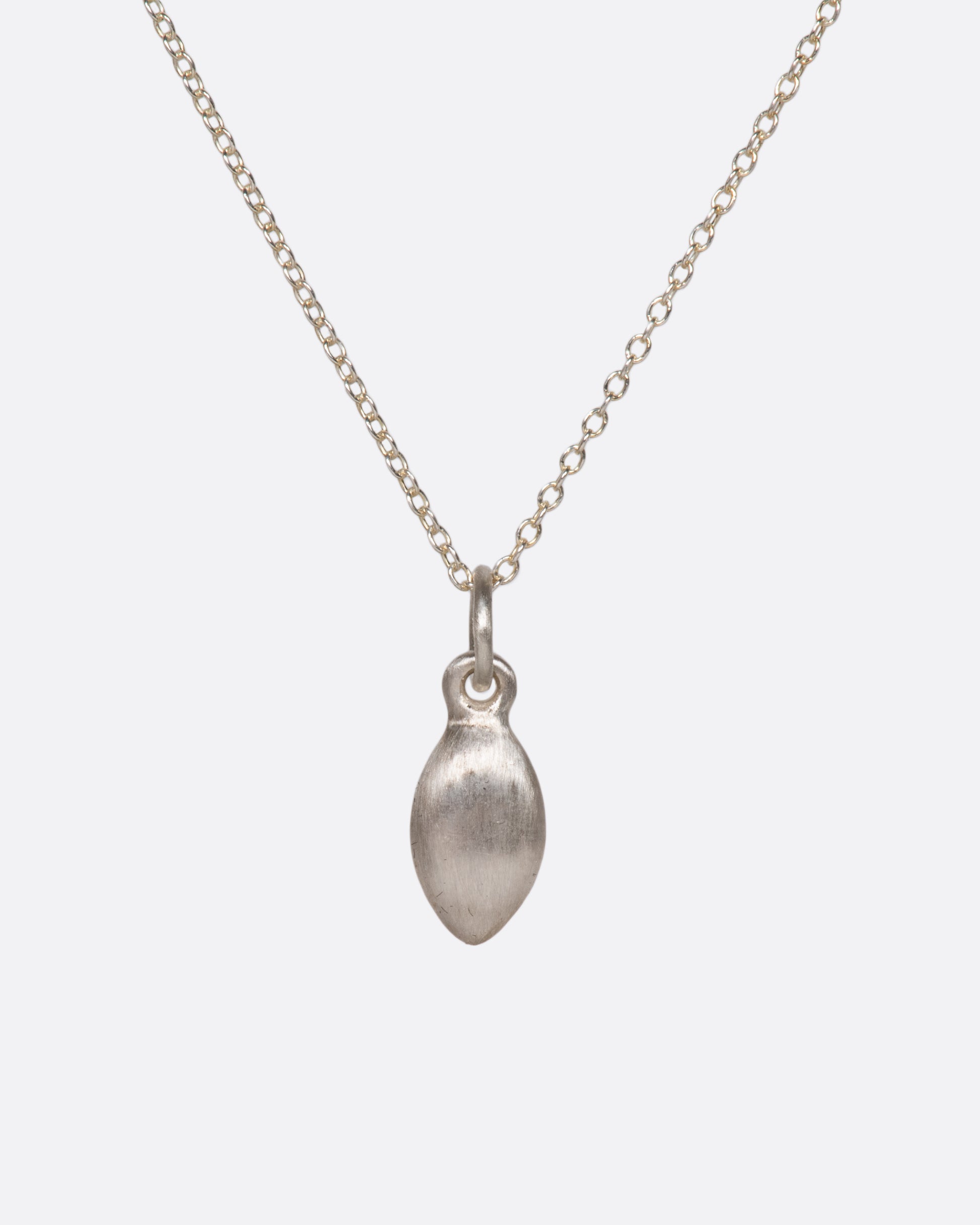 A silver cable chain necklace with a seed shaped pendant with three diamonds and oxidized etching. Shown from the back.