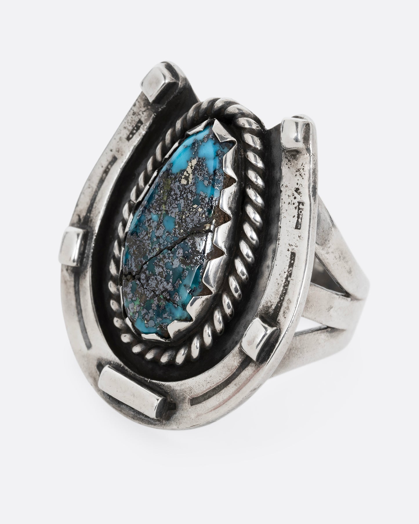 A silver horseshoe ring with a free- form turquoise in the center. Shown from the front.