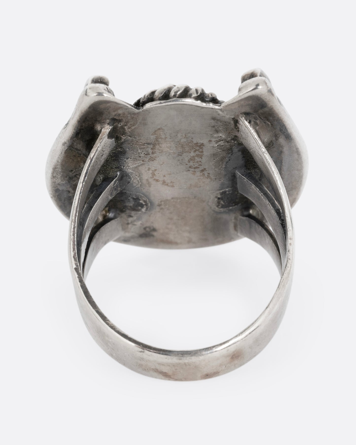 A silver horseshoe ring with a free- form turquoise in the center. Shown from the back.