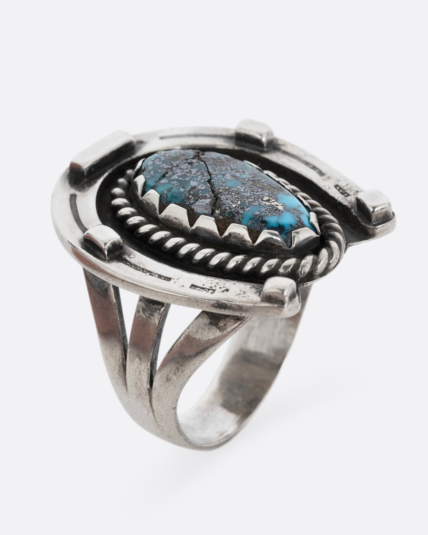 A silver horseshoe ring with a free- form turquoise in the center. Shown from the top.