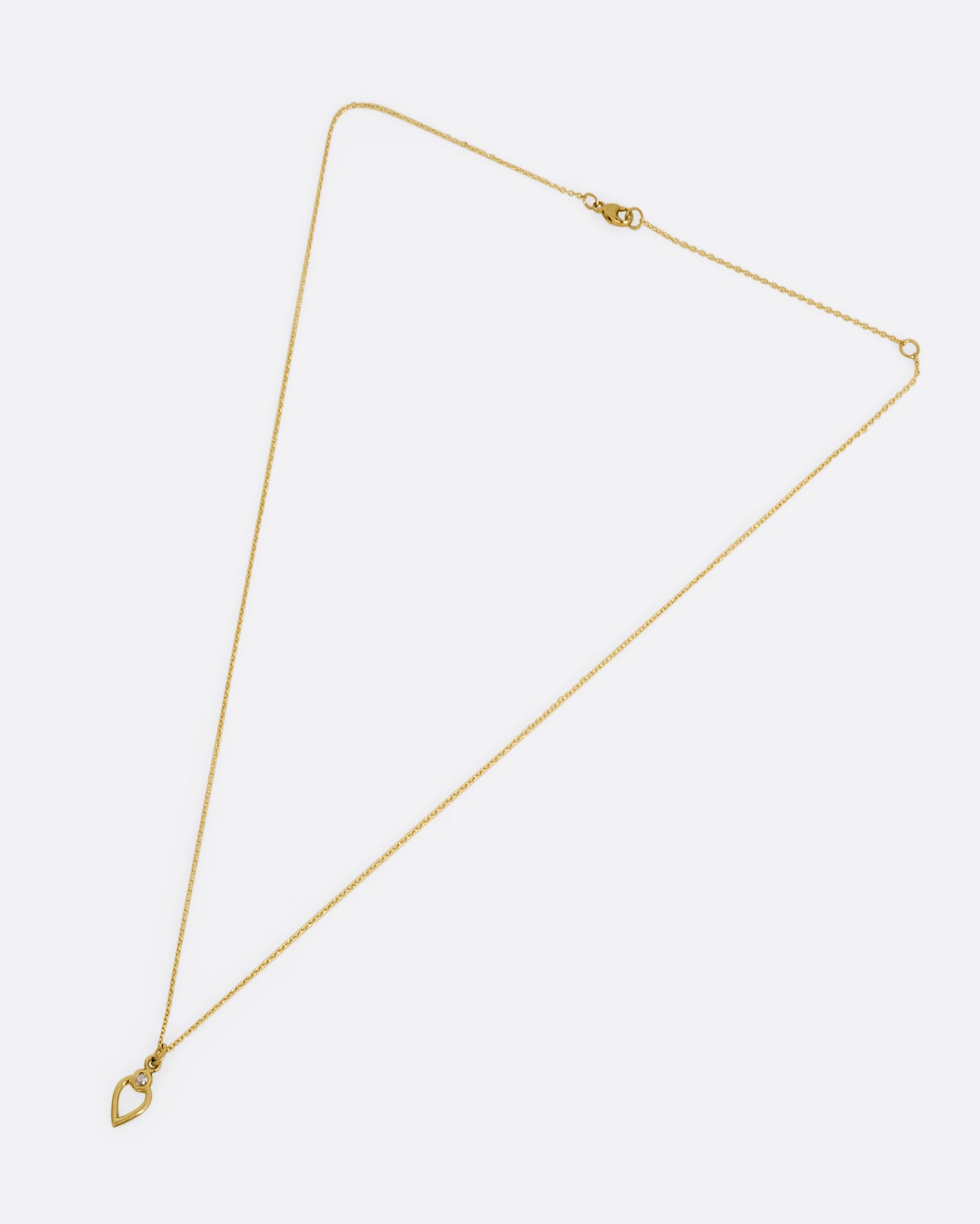 A yellow gold necklace with an open heart pendant with a diamond. Shown clasped lying flat.