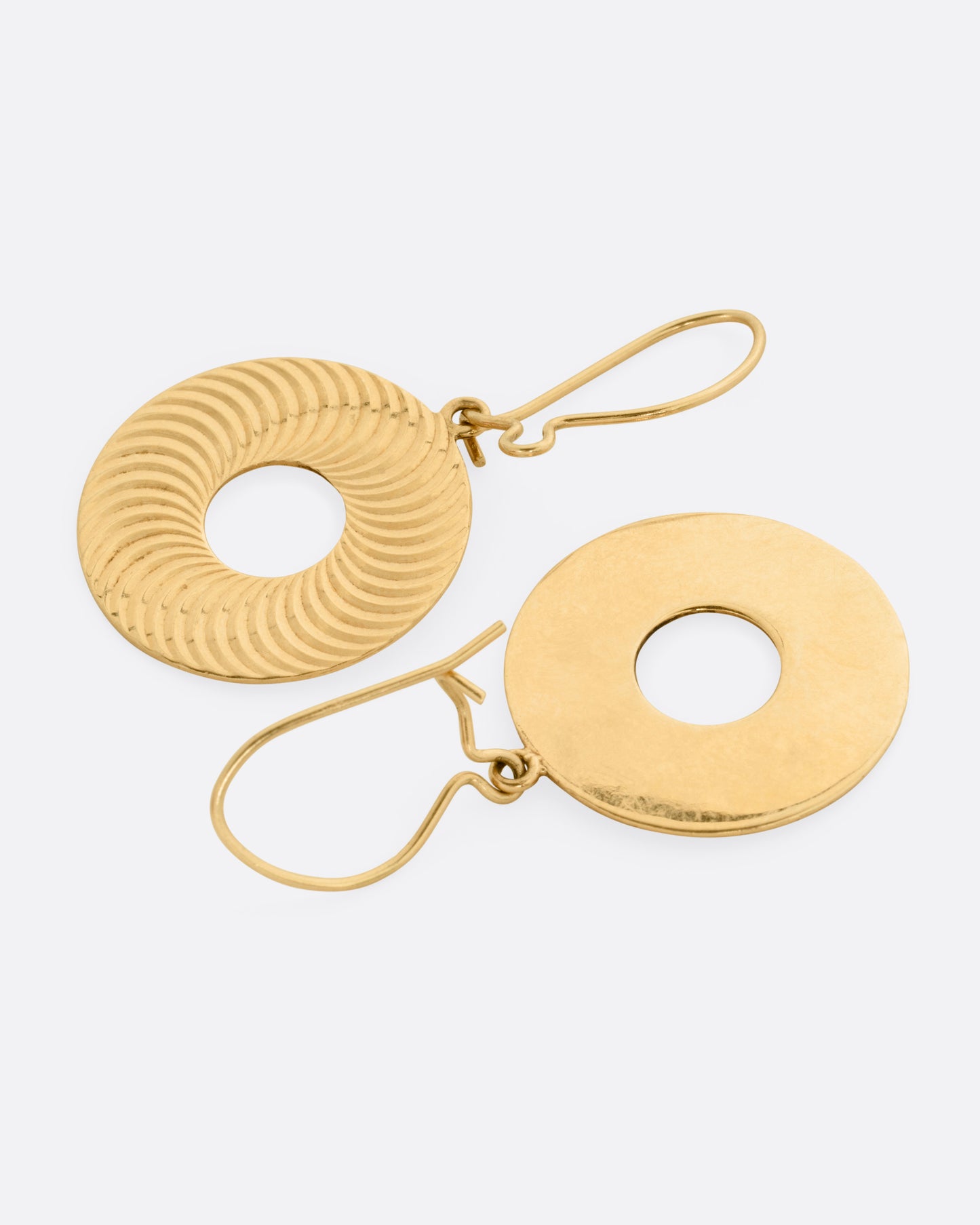 A pair of round yellow gold drop earrings with open centers and an illusional pattern, shown lying flat.