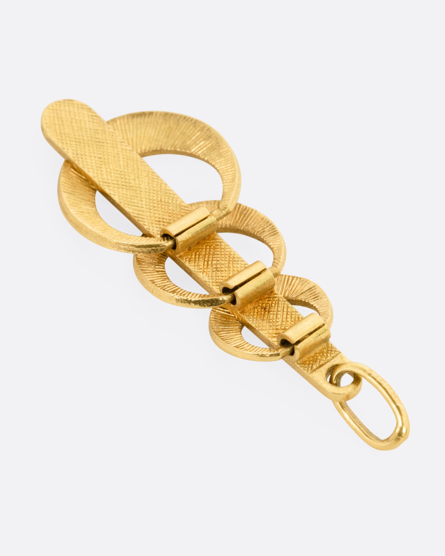 A yellow gold pendant with three enamel crescents in blue and green on a red enamel bar. Shown from the back.