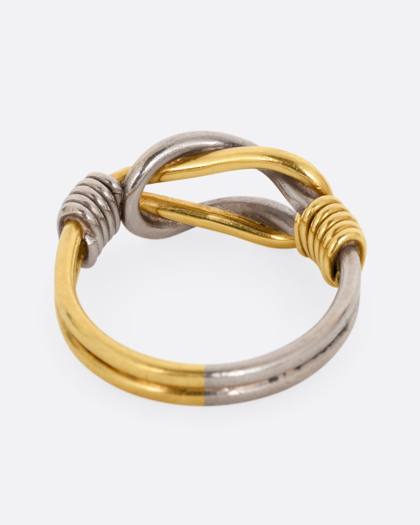 A white and yellow gold infinity knot ring. Shown from the back.