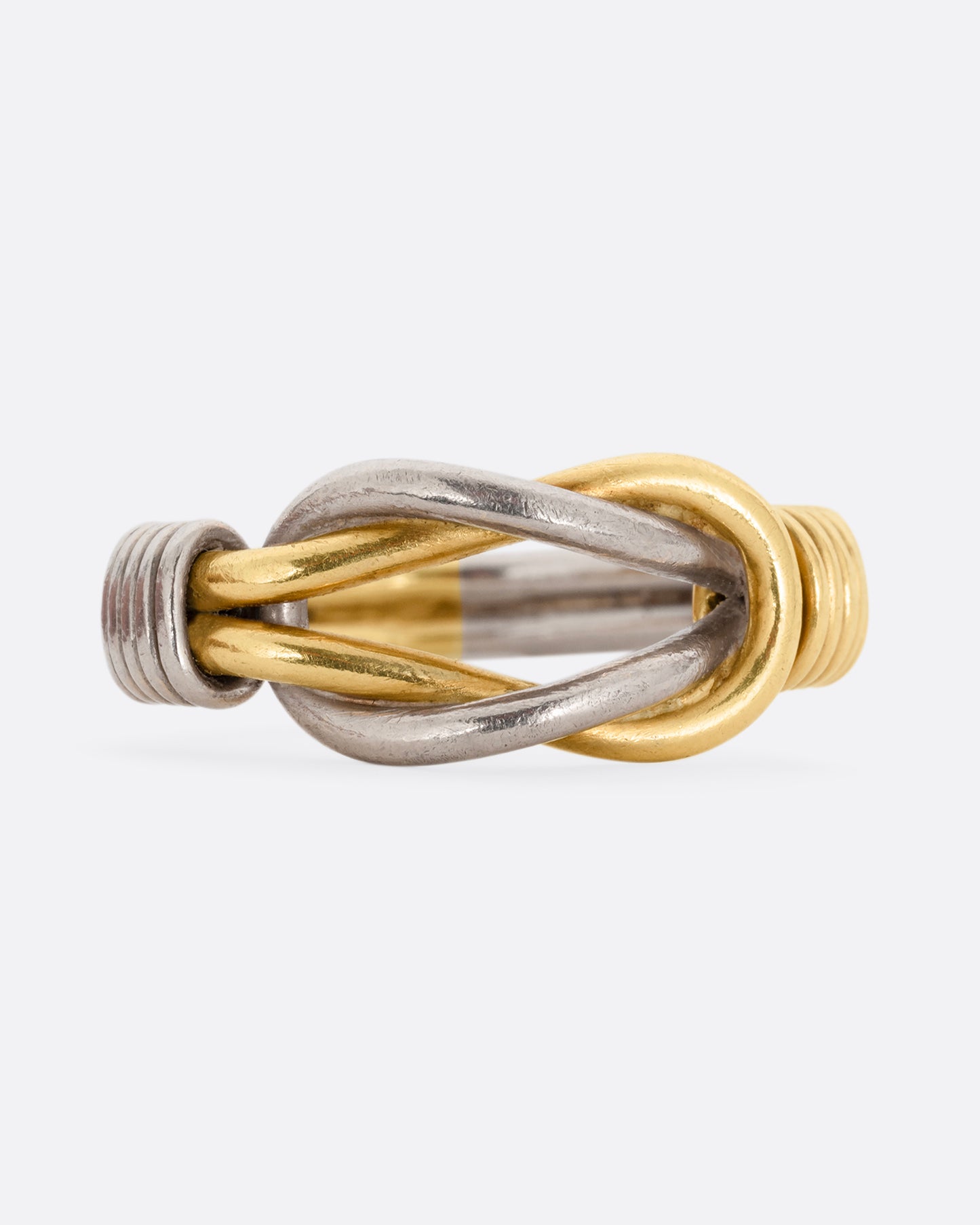 A white and yellow gold infinity knot ring. Shown from the front.