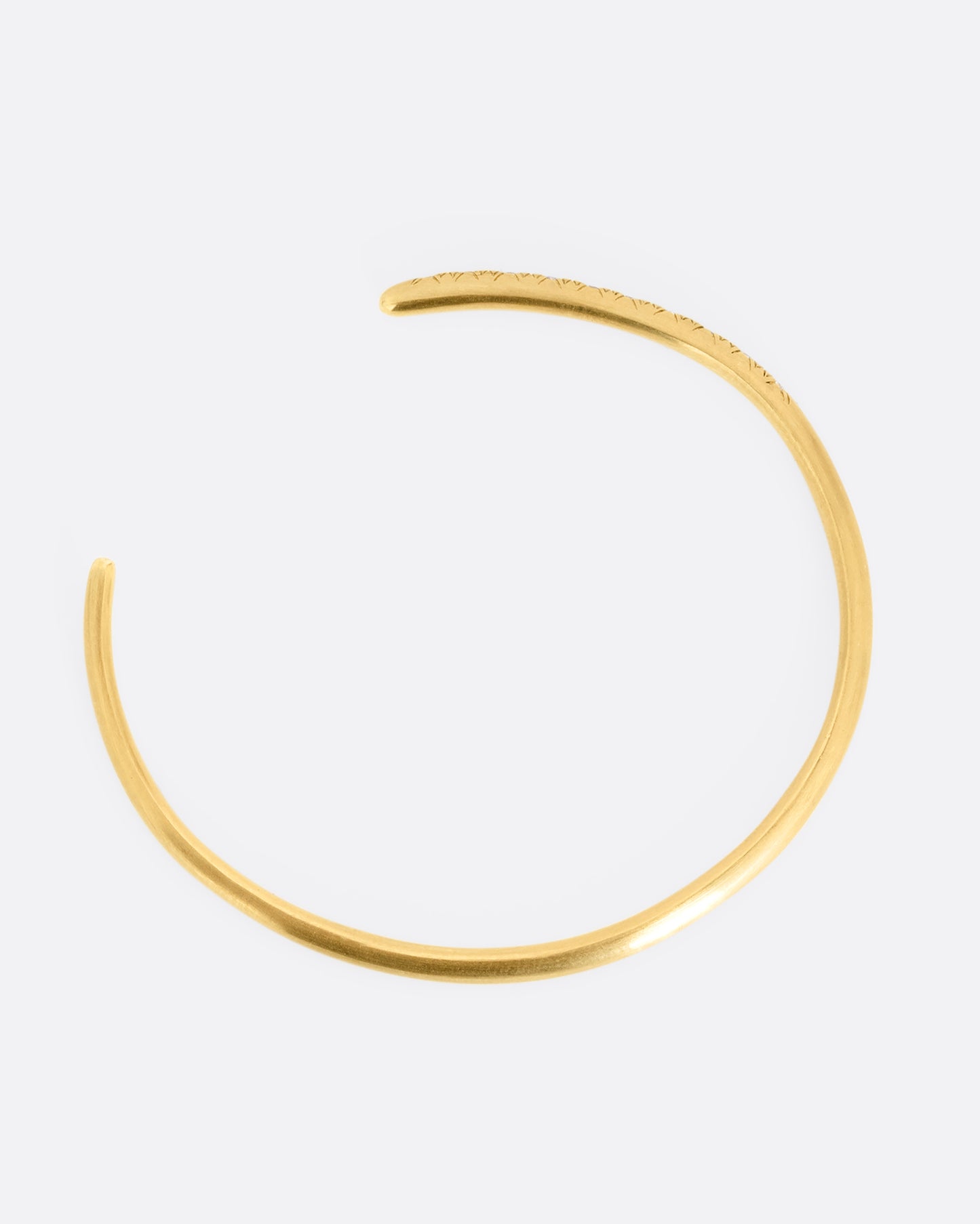 A yellow gold open cuff bracelet with diamonds. Shown from above.