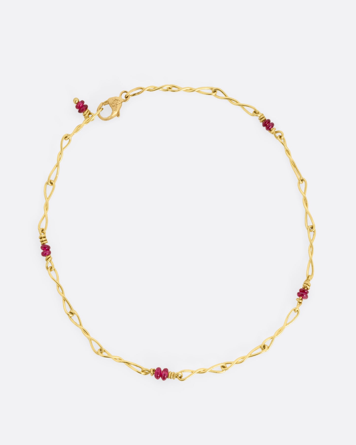 A yellow gold twisted paperclip chain link bracelet with five ruby beads.Shown clasped from the top.