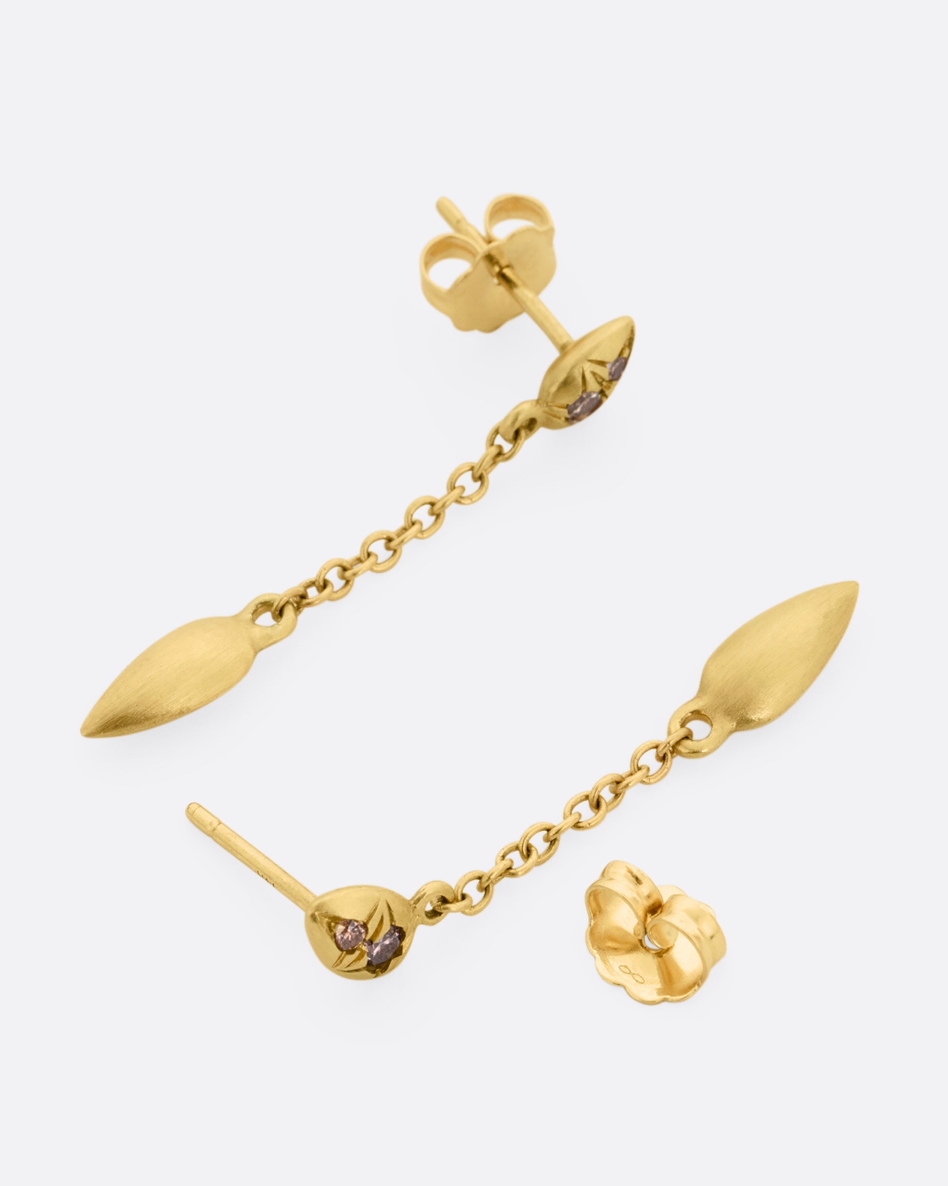 Yellow gold earrings with brown diamonds and cable chain drops. One earring is shown lying flat diagonally from the front. The other earring is shown open lying flat from the back.