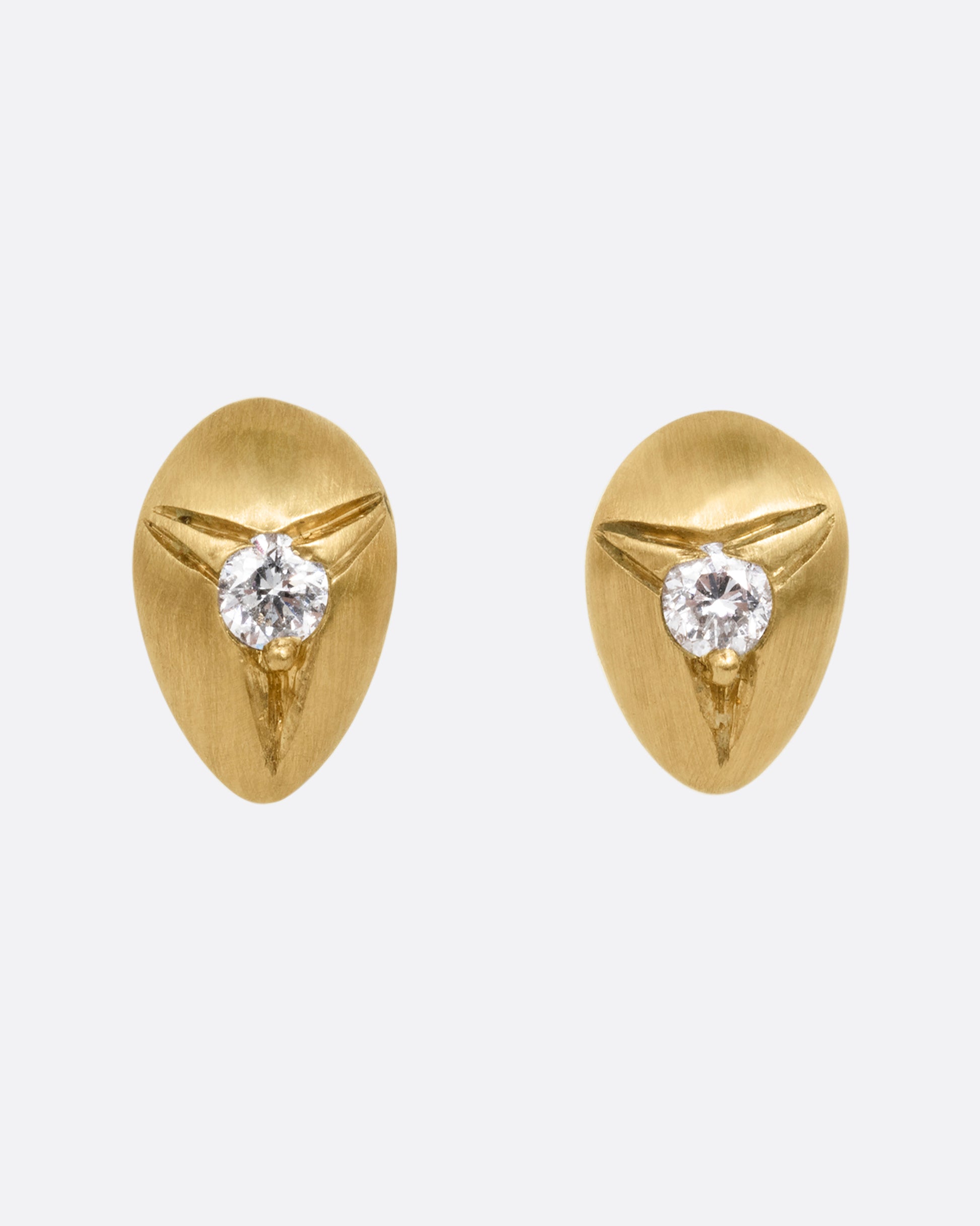 Yellow brushed gold teardrop shaped earrings with white diamonds at the center. Shown from the front.