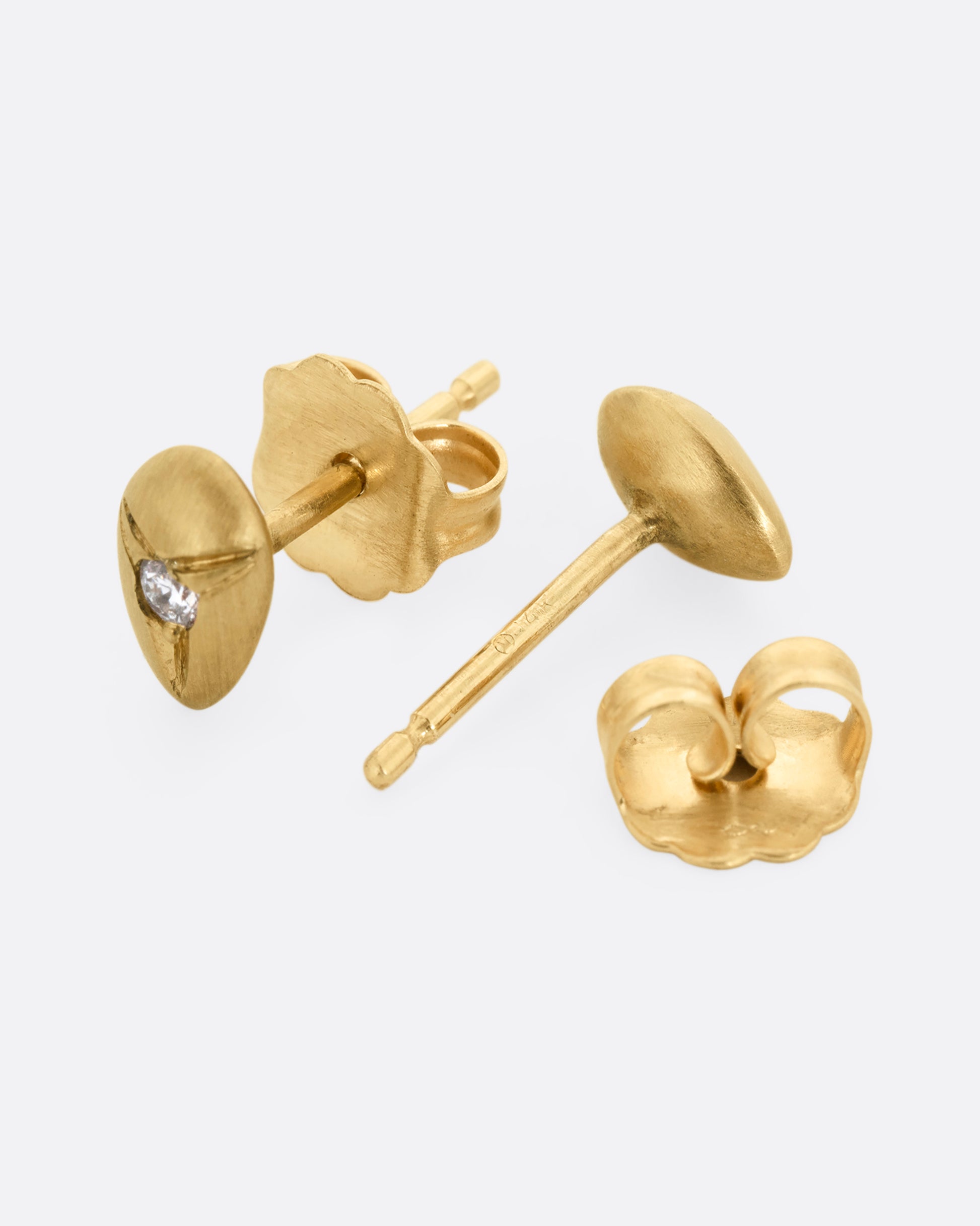 Yellow brushed gold teardrop shaped earrings with white diamonds at the center. One earring is shown lying flat from the front. The other earring is shown lying flat open from the back.