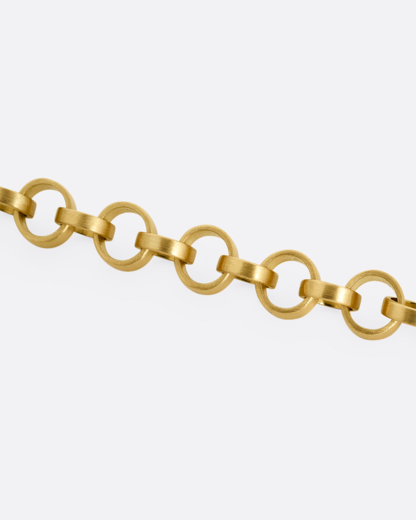 A yellow gold bracelet with bicycle chain inspired links. Shown close up.