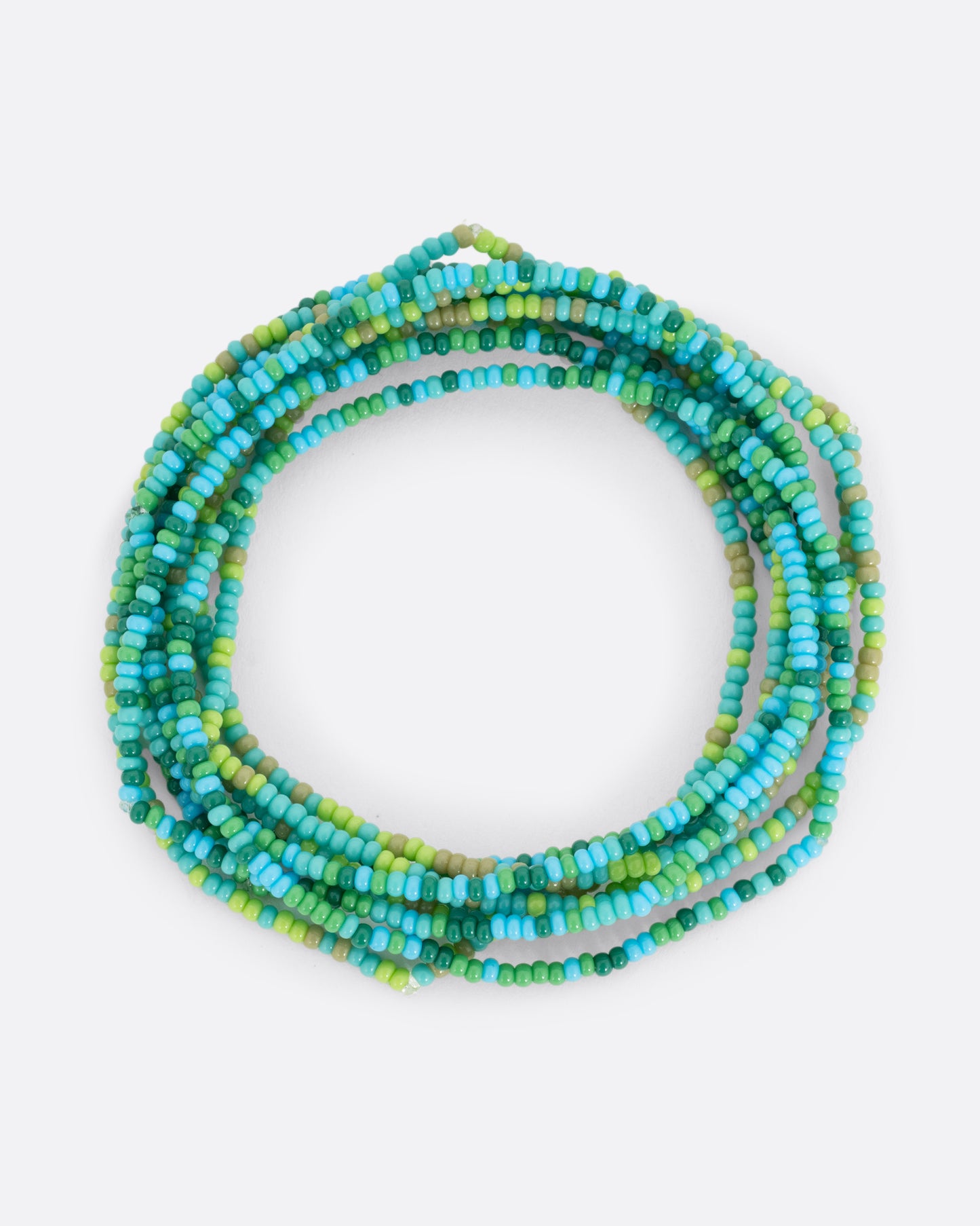 A stretchy bracelet with seed beads in blue and green shown in a stack.