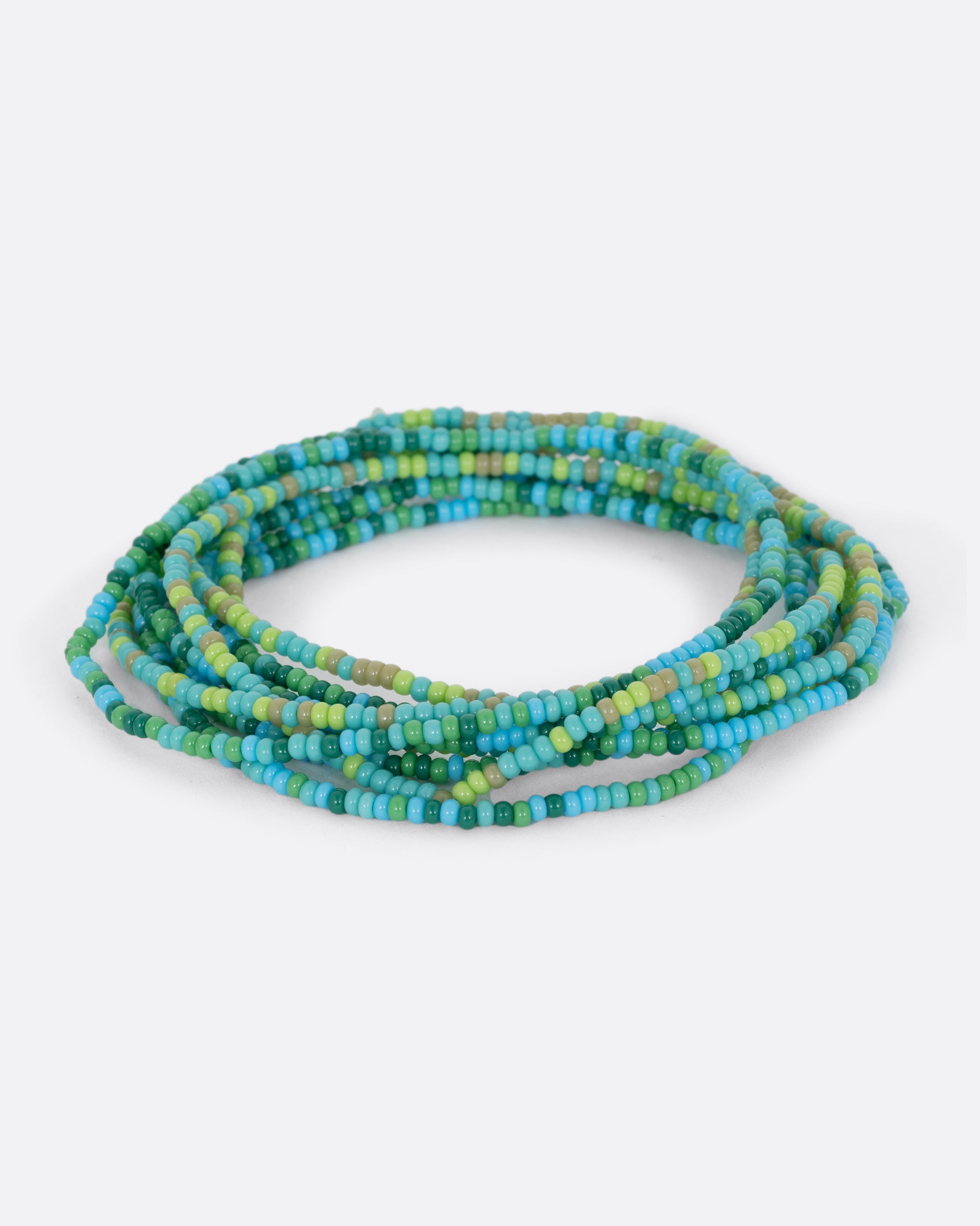 A stretchy bracelet with seed beads in turquoise and olive. View of both colors in a stack.