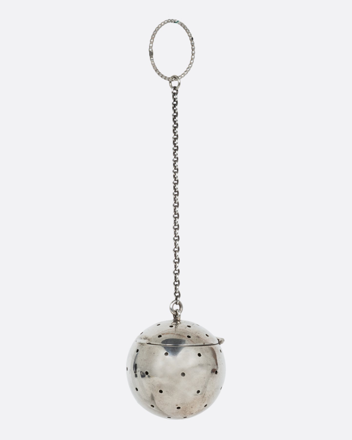 A silver spherical tea infuser topped with a hinged lid. Shown from the side.