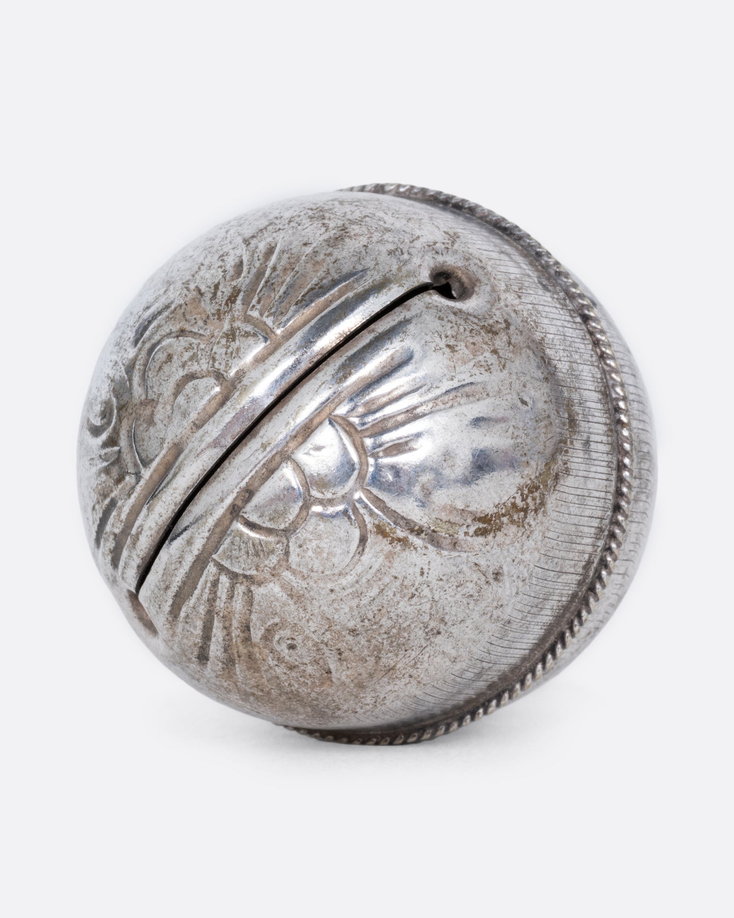 A silver engraved bell charm. Shown from the bottom.