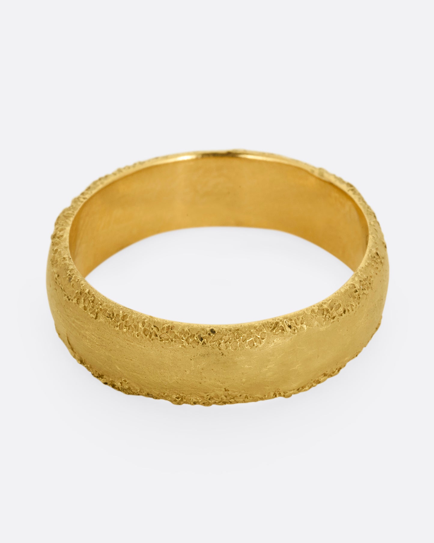 A yellow gold band with a matte center and textured edges. Shown from slightly above.