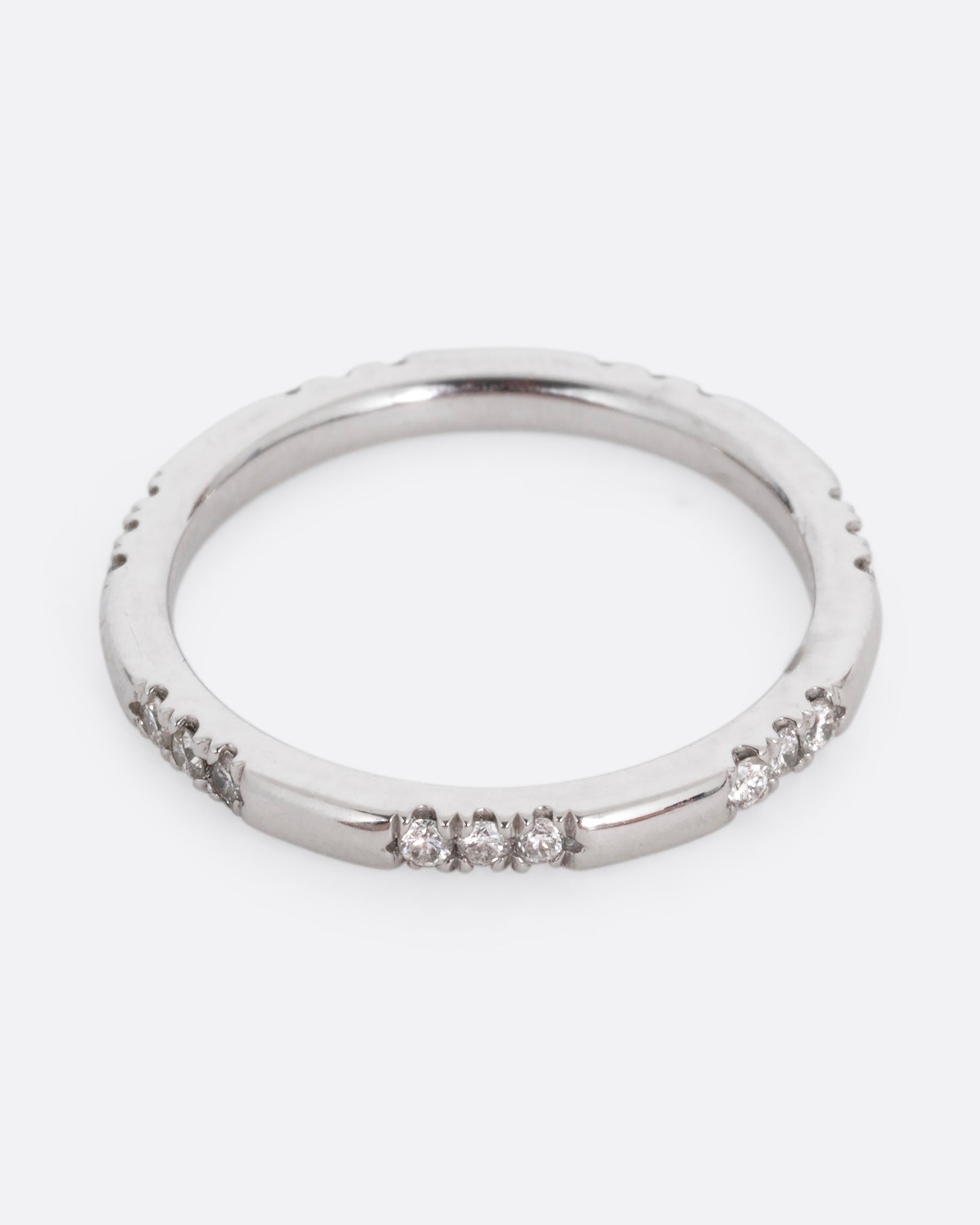 A platinum ring with stations of white diamonds. Shown from the front.