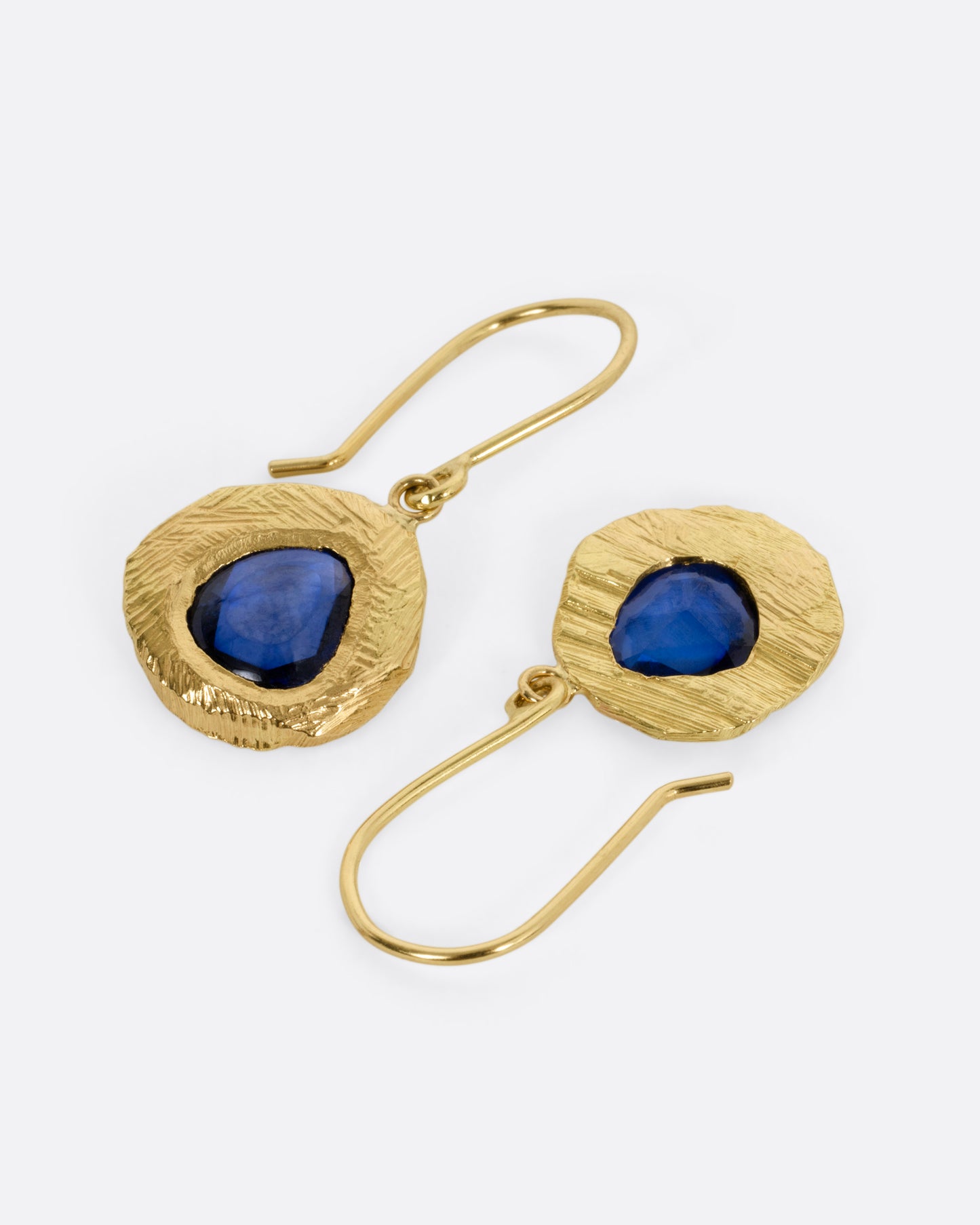 A pair of yellow gold drop earrings with blue sapphires. One earring is shown from the front, the other from the back.