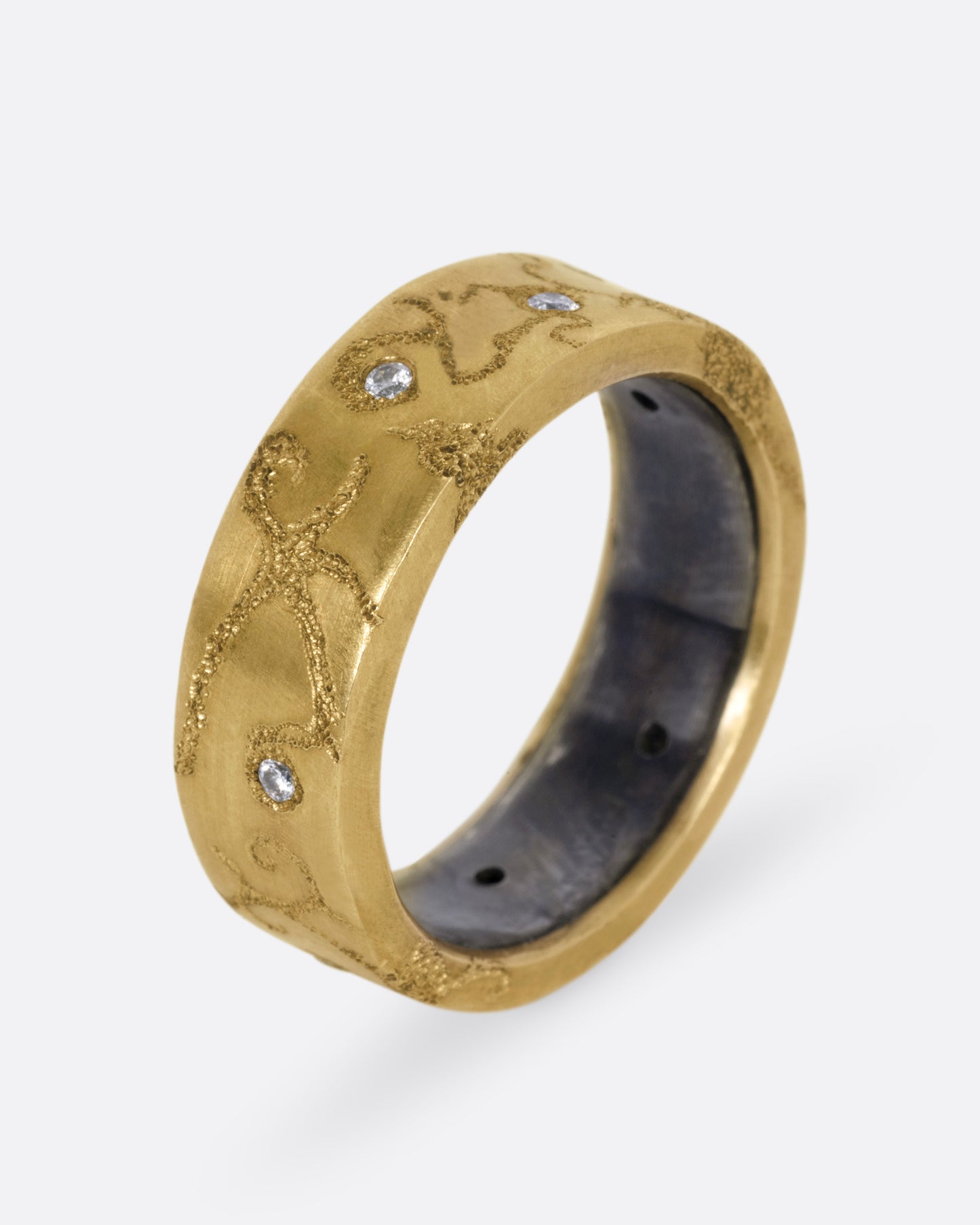 A yellow gold ring with etched oceanic images and diamond accents throughout, shown from the side standing up.