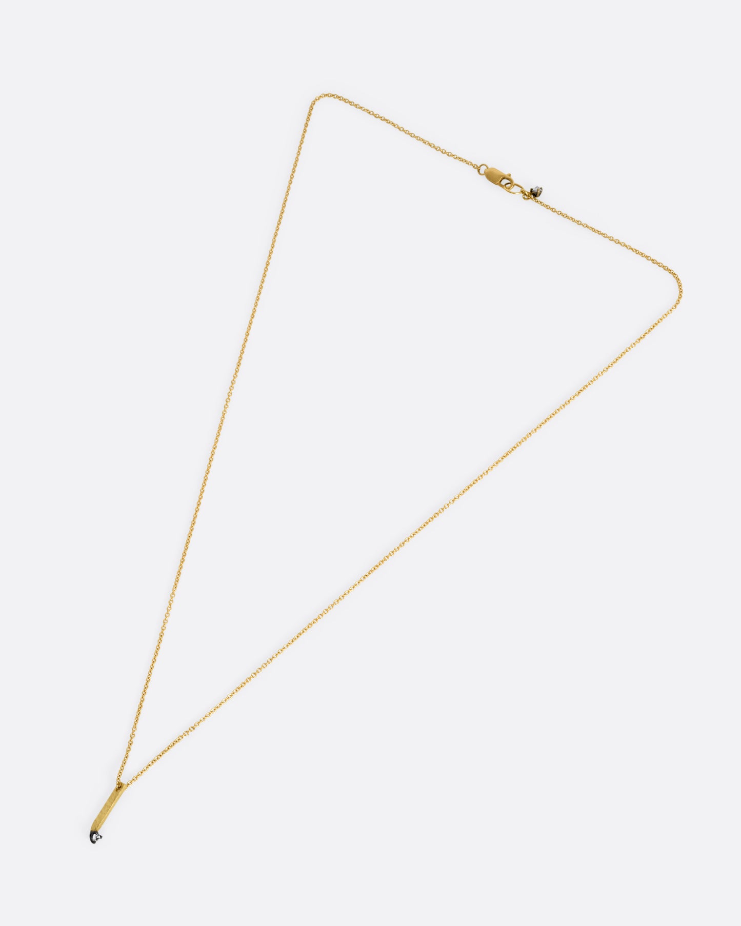 A yellow gold cable chain necklace with a bar pendant studded with an inverted diamond, shown lying flat from the front.