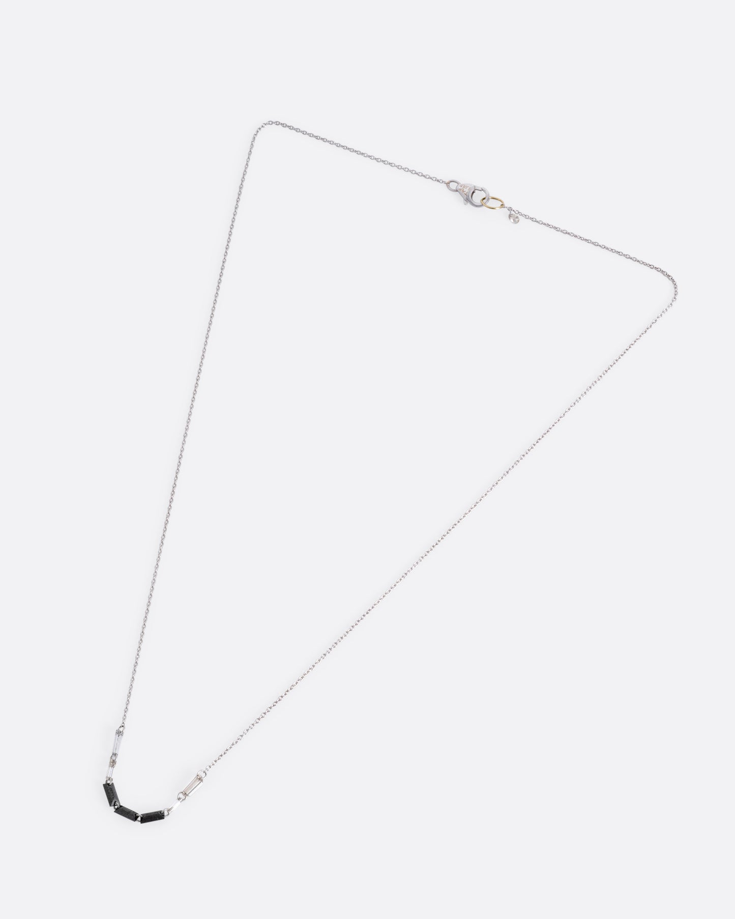A white gold cable chain with black and white baguette diamonds connected by platinum jump rings, shown from the front.