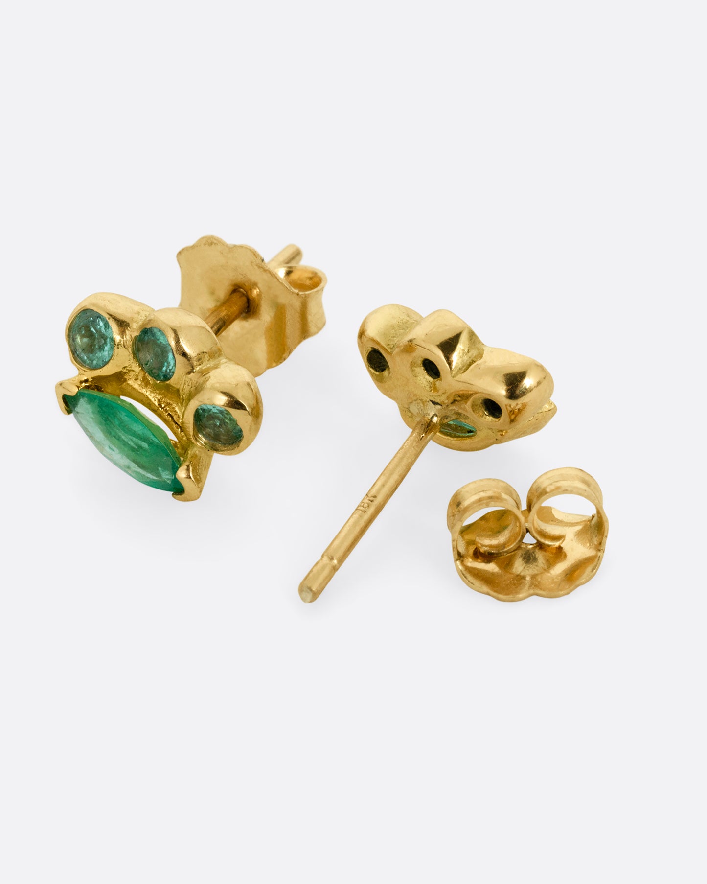 A pair of yellow gold stud earrings with round and marquise emeralds. Shown lying flat; one from the front, the other open from the back.
