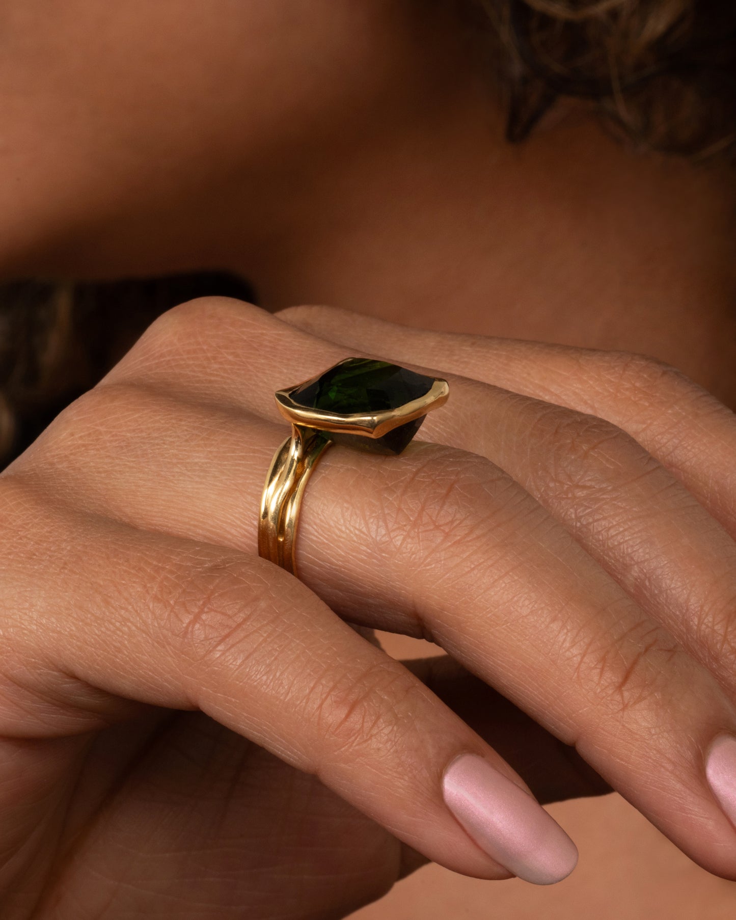 This ring is designed to showcase the tourmaline; the band is set off to one side and the setting is raised to allow for maximum light to pass through the stone. Shown on a finger.