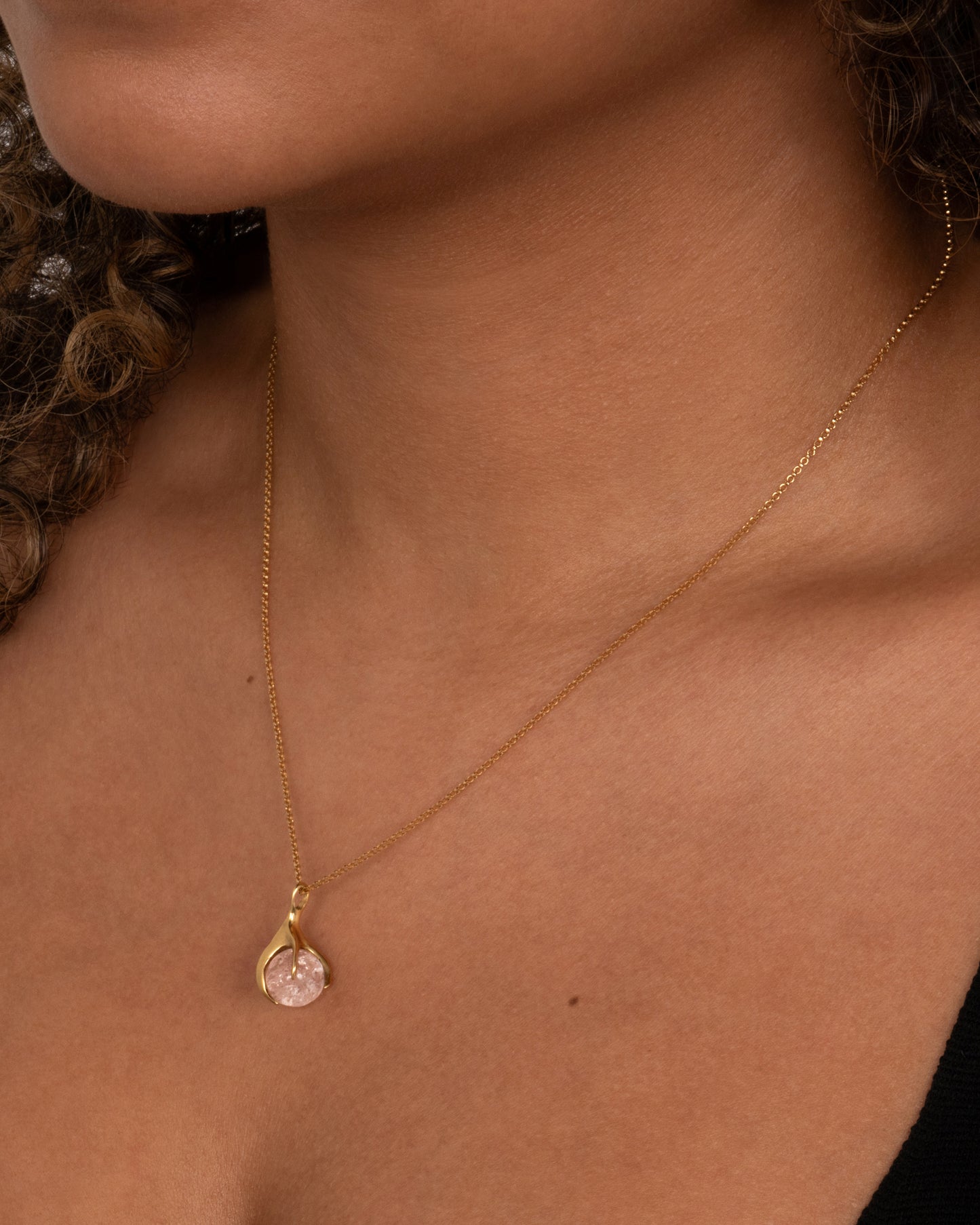 A pale pink tourmaline sphere is set in a gold claw setting for a substantial, yet airy pendant. Shown worn around the neck.