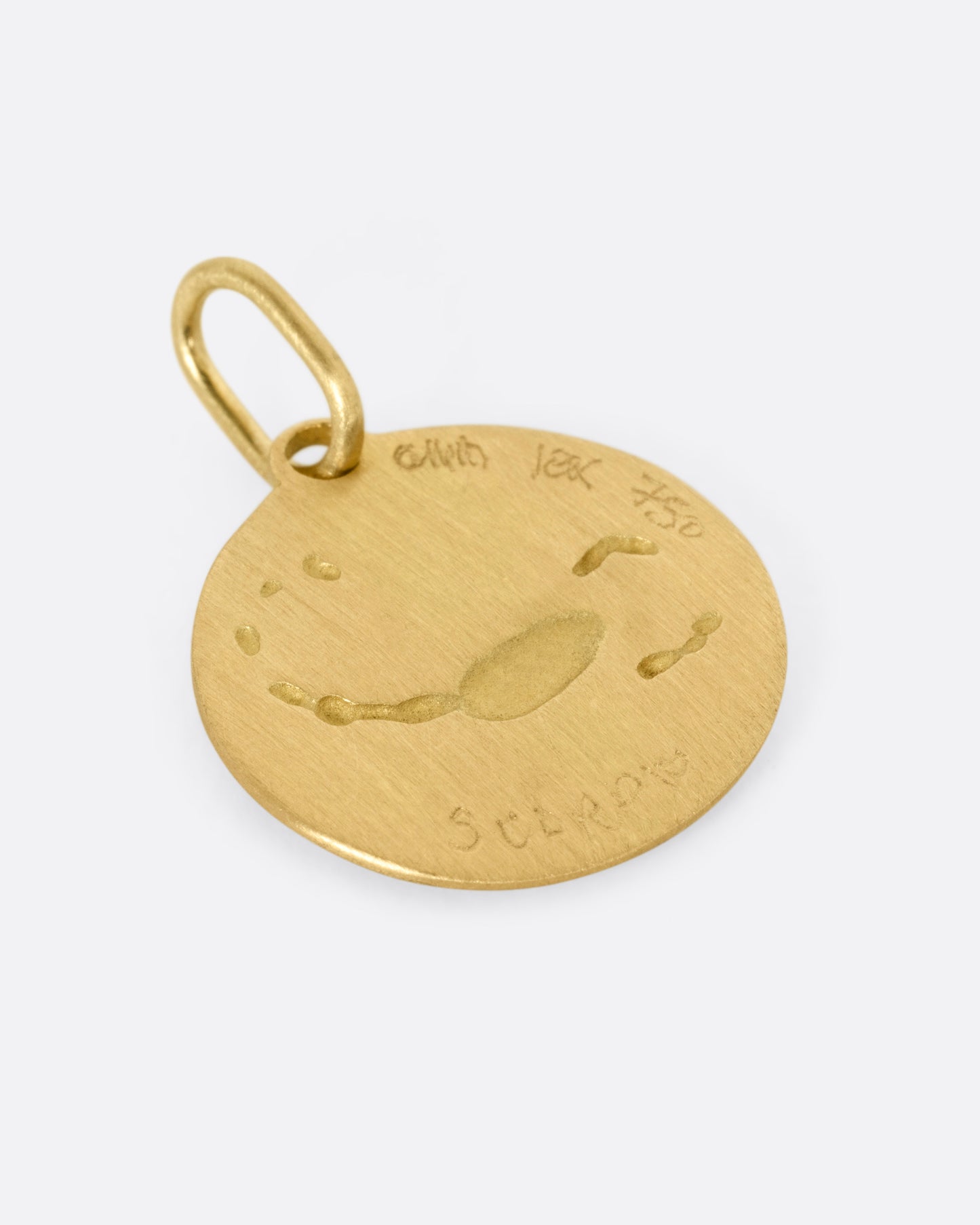 A circular yellow gold Scorpio pendant with a scorpion on its front, shown from the back.
