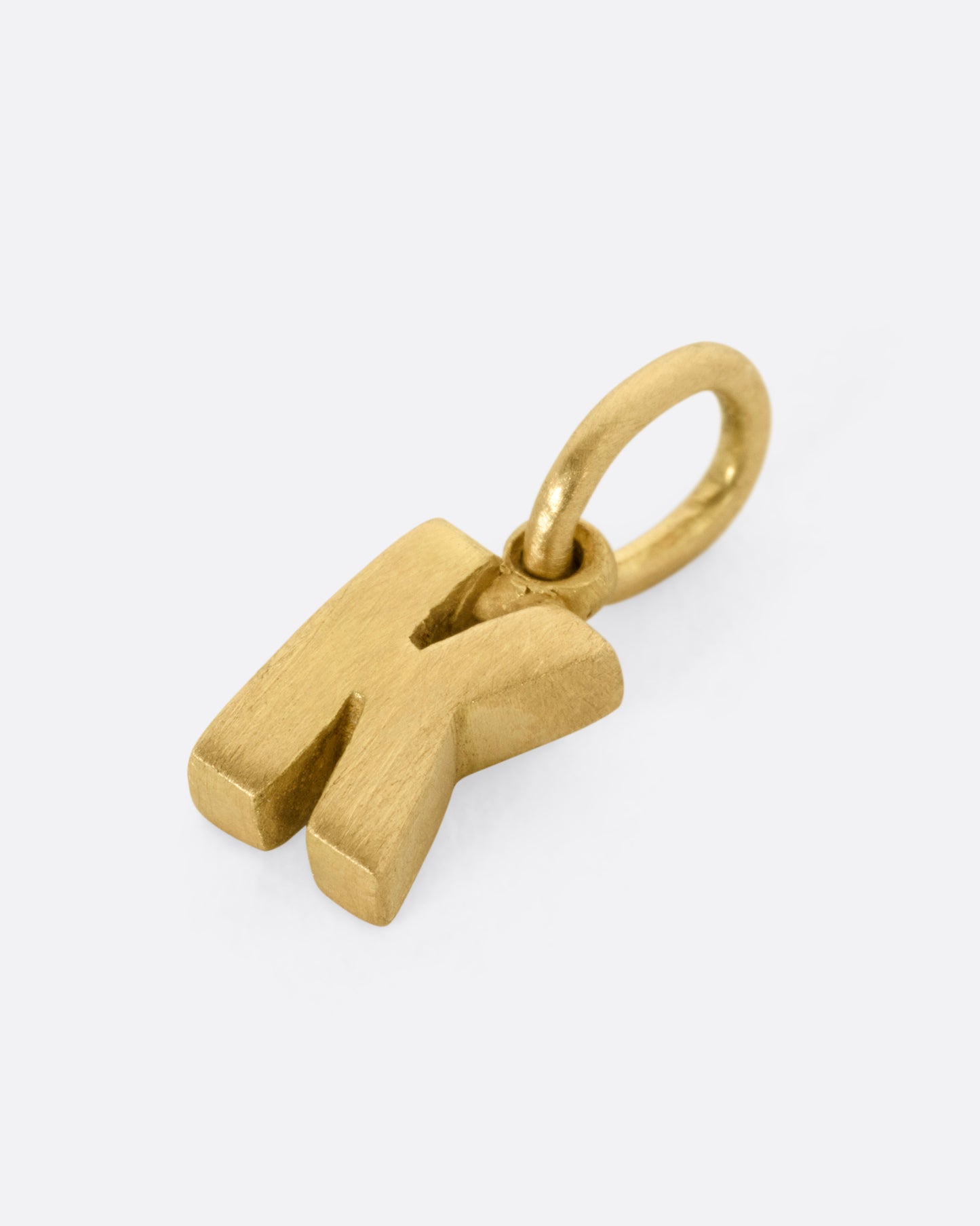 A yellow gold letter 'K' pendant shown from the side.