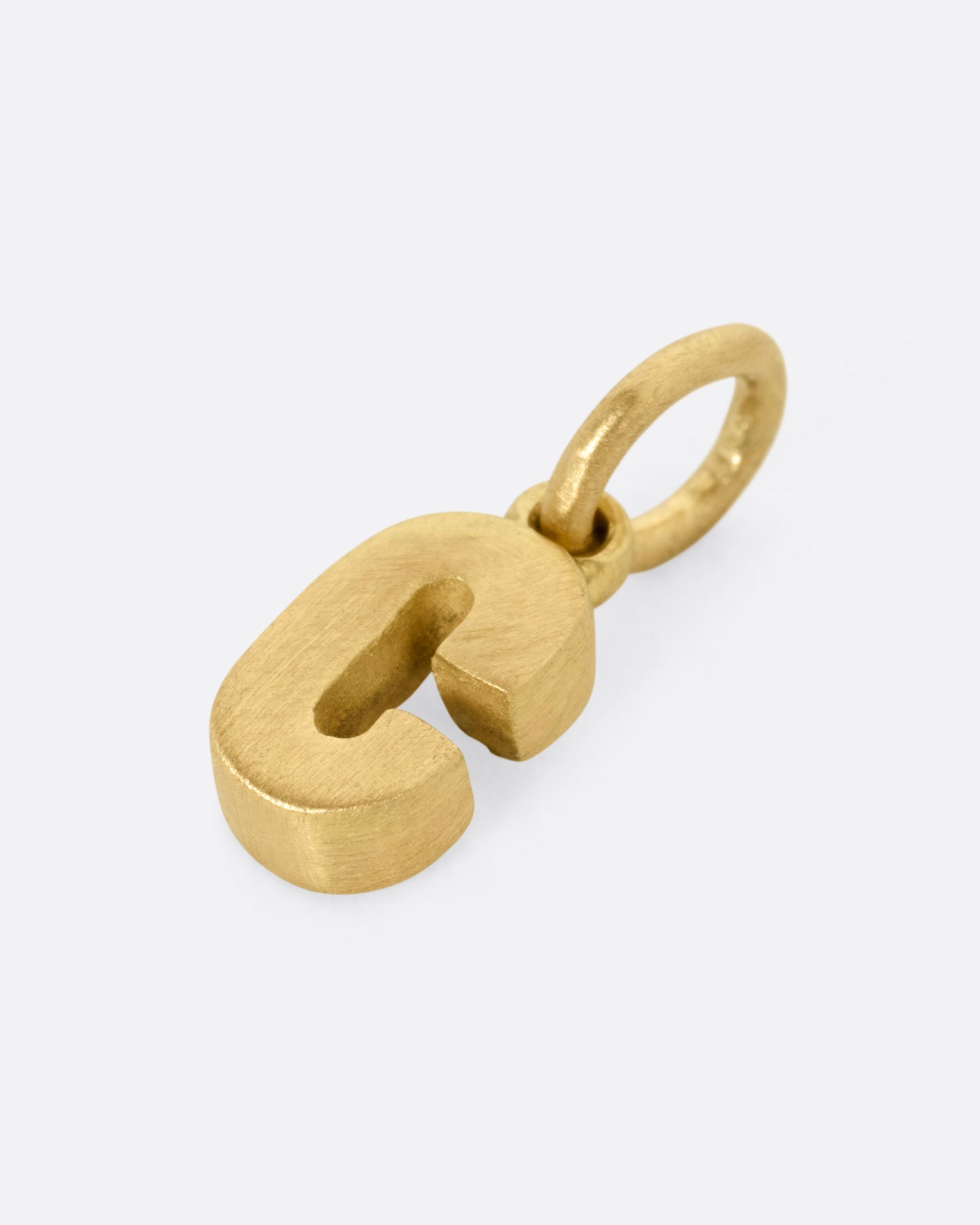 A yellow gold letter 'C' pendant shown from the side.