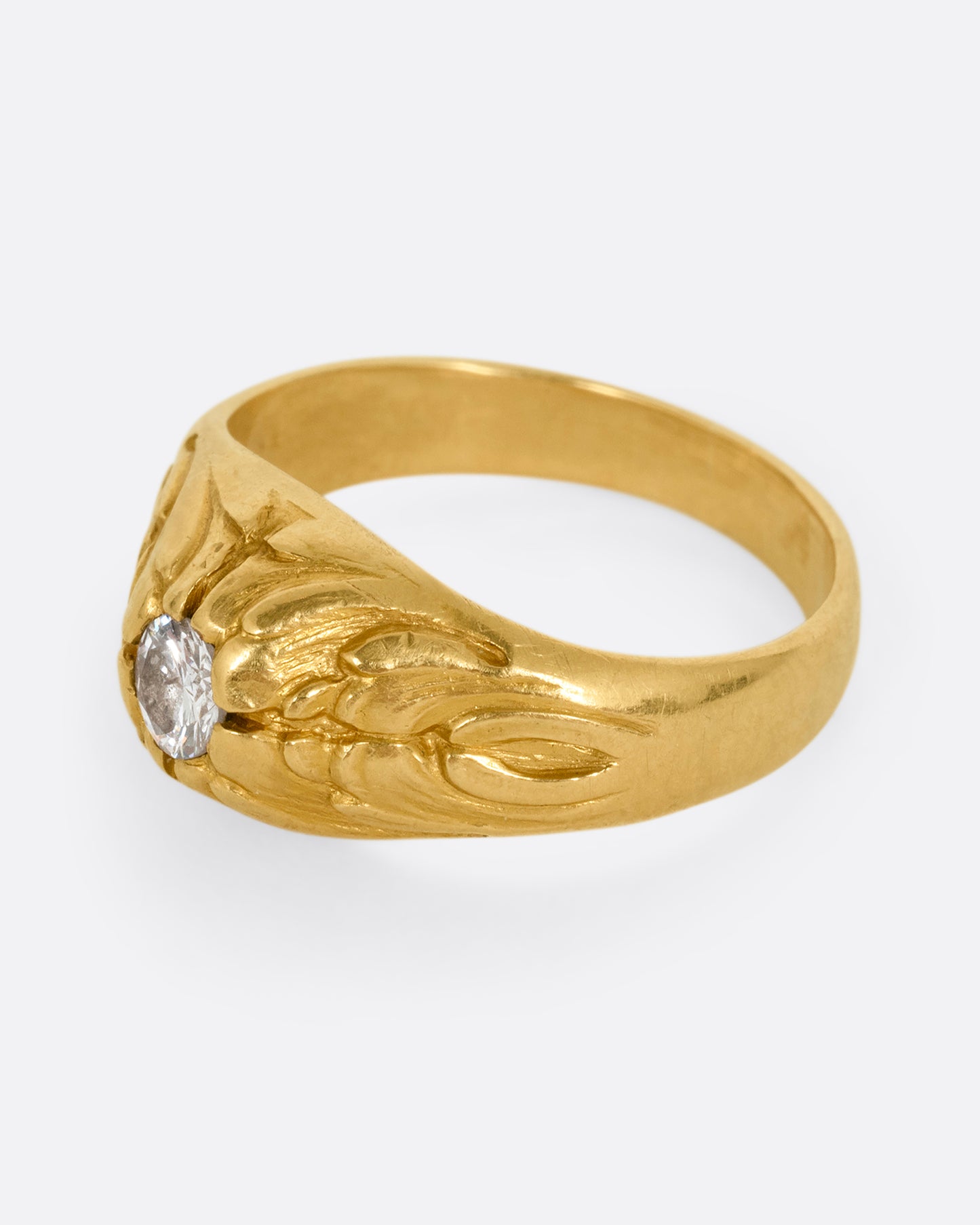 A yellow gold dome ring with textural waves on its top and a round central diamond. Shown from the side.