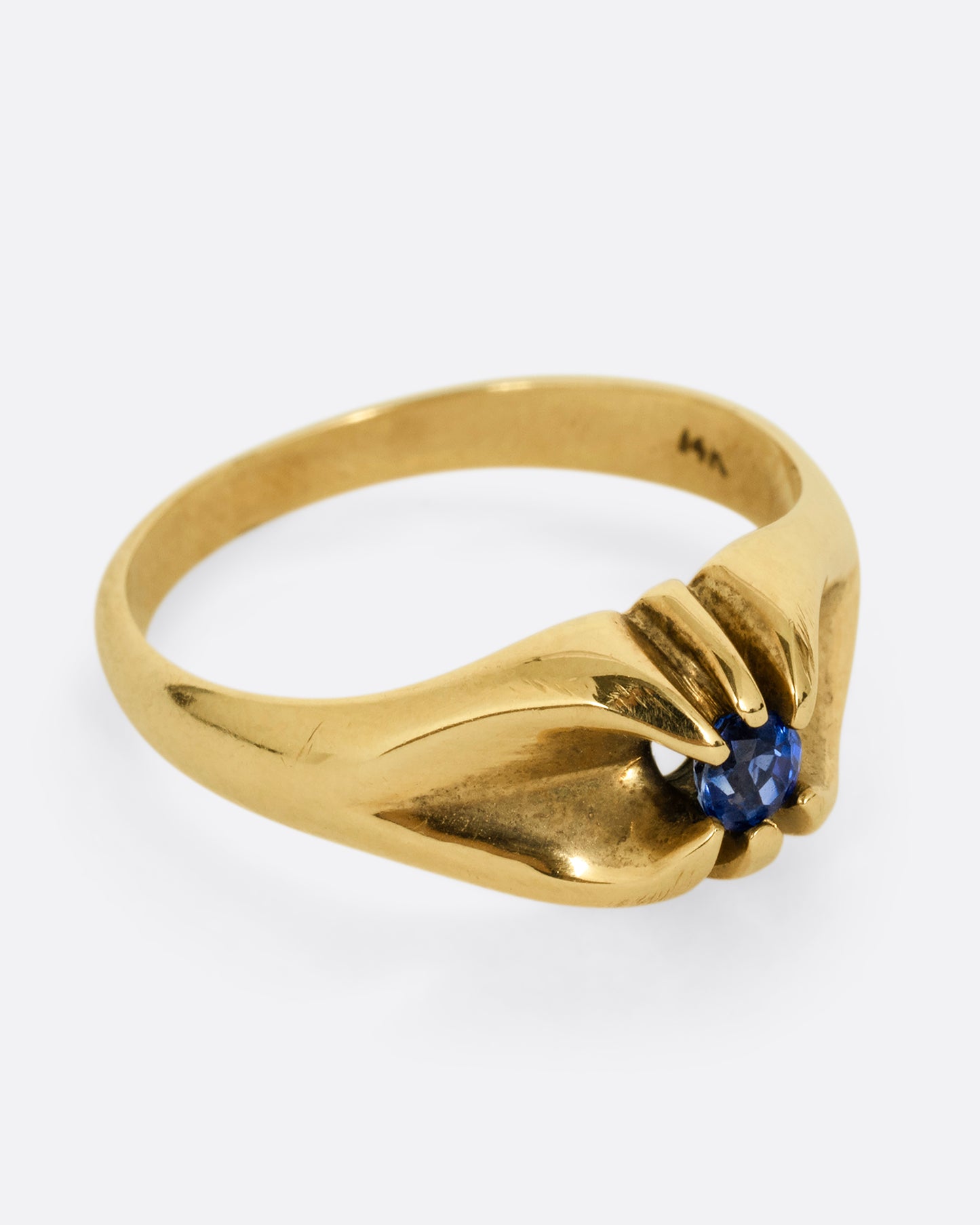 A yellow gold ring with a prong set blue sapphire. Shown from the side.