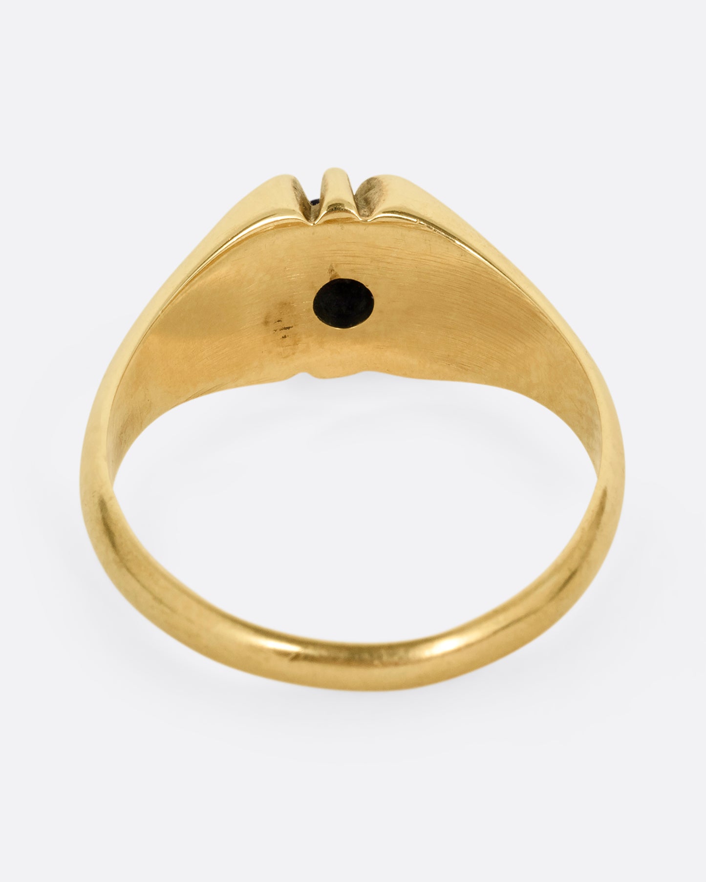 A yellow gold ring with a prong set blue sapphire. Shown from the back.