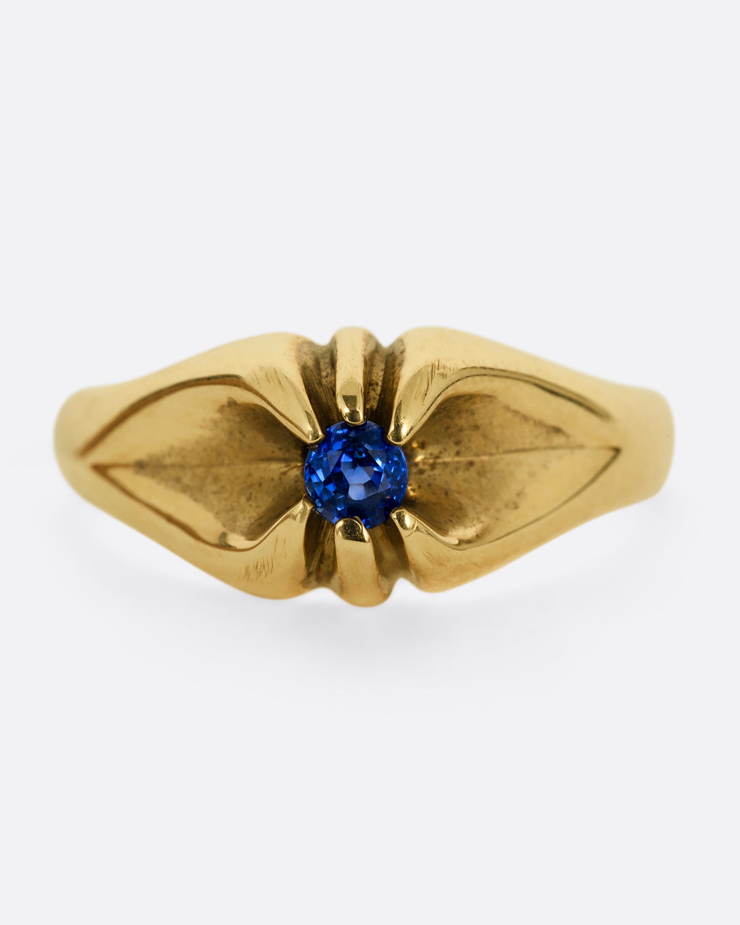 A yellow gold ring with a prong set blue sapphire. Shown from the front.