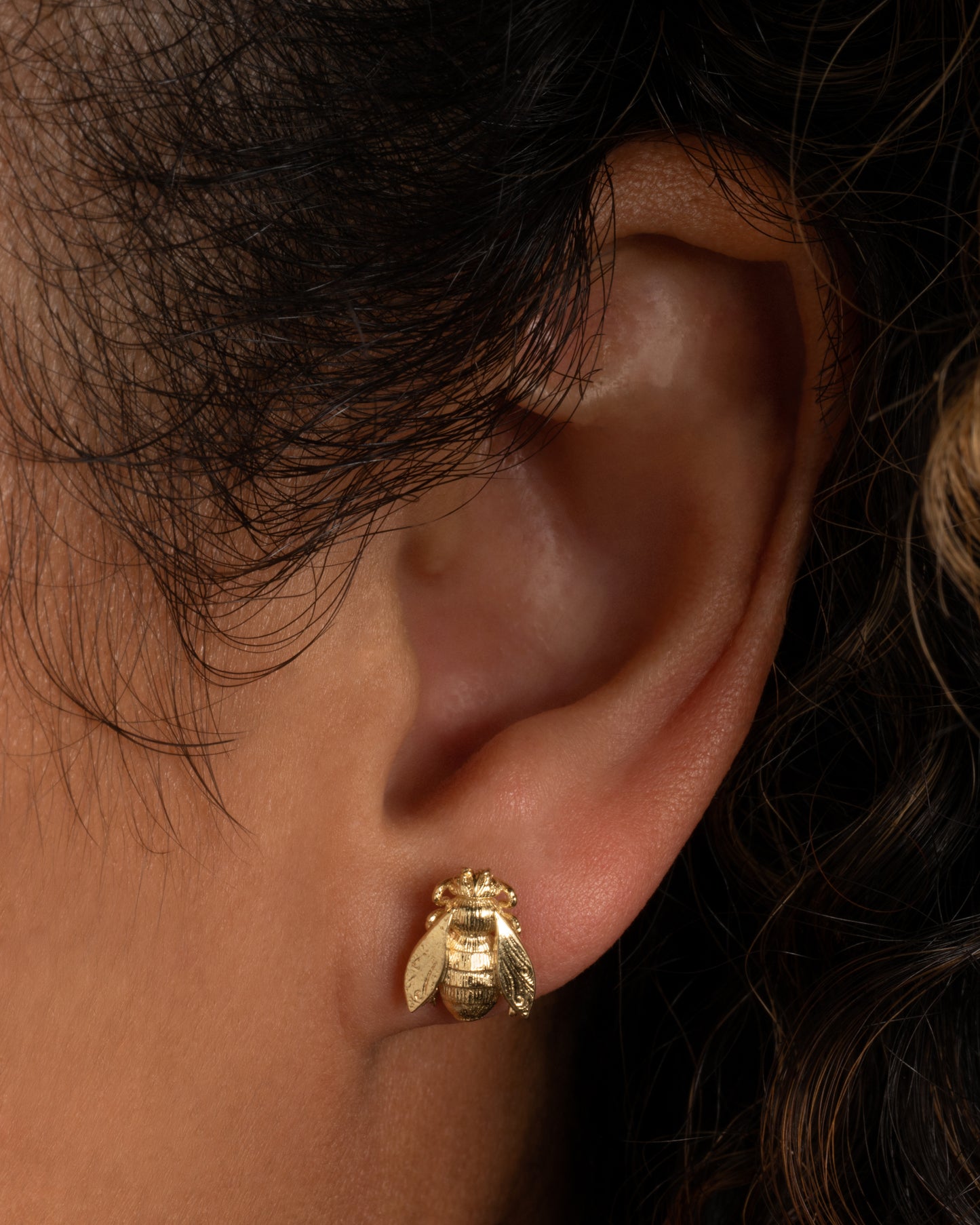 A yellow gold bee earring. Shown on a person from the front.