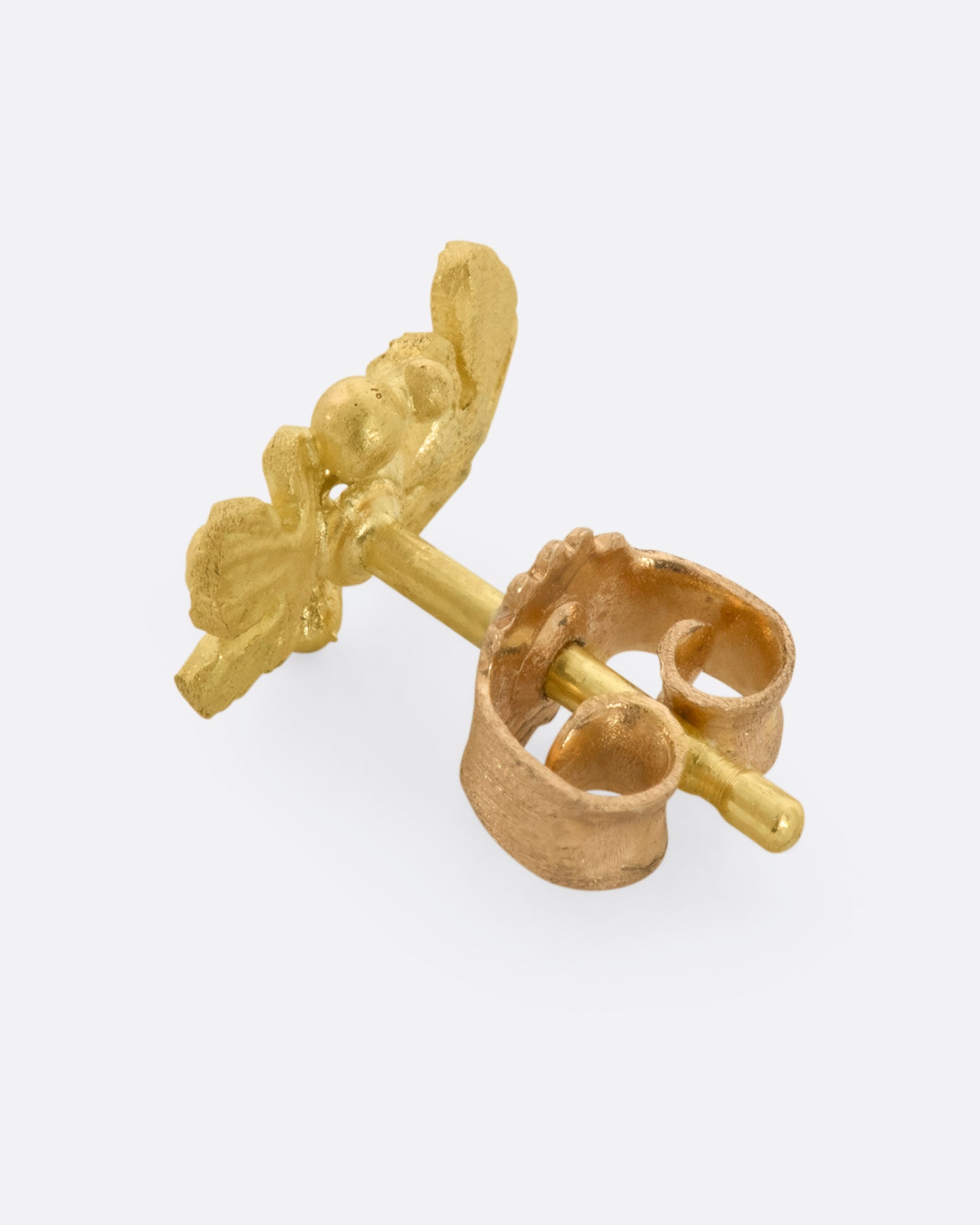 A yellow gold earring with two flowers, one with a diamond at the center. View from the back including gold backing..