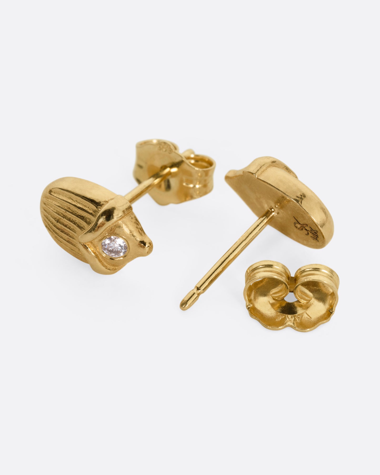 A pair of yellow gold scarab shaped stud earrings, each punctuated by a diamond. One earring is shown from the front, the other open from the back.