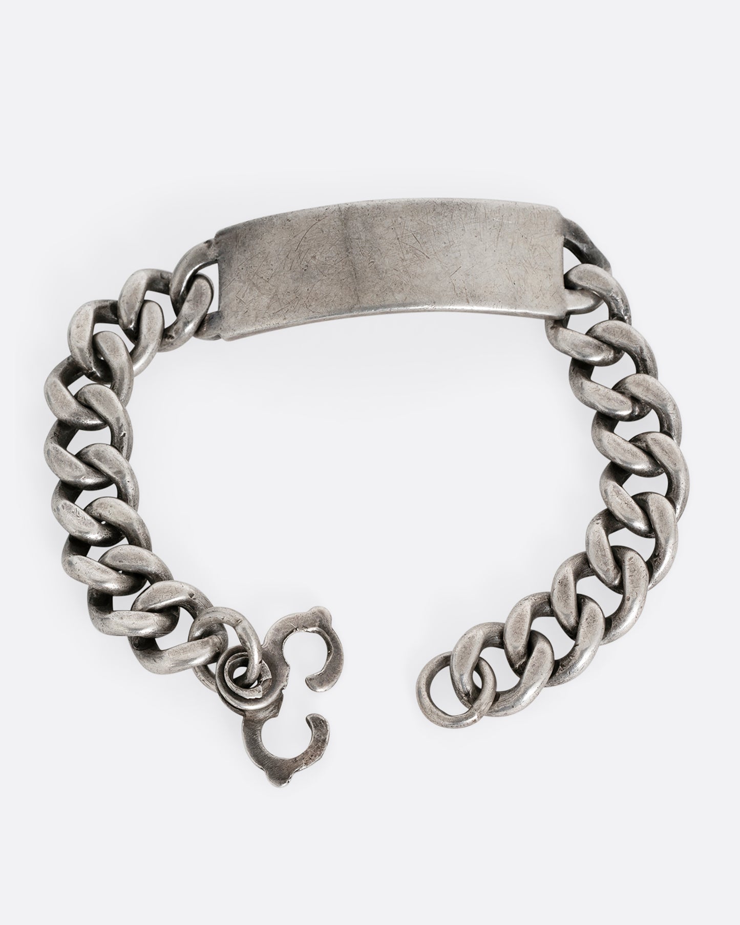A silver cable chain ID bracelet with "A.R. Warren" in curling script engraved on the inside of its name tag. Shown open from the front.