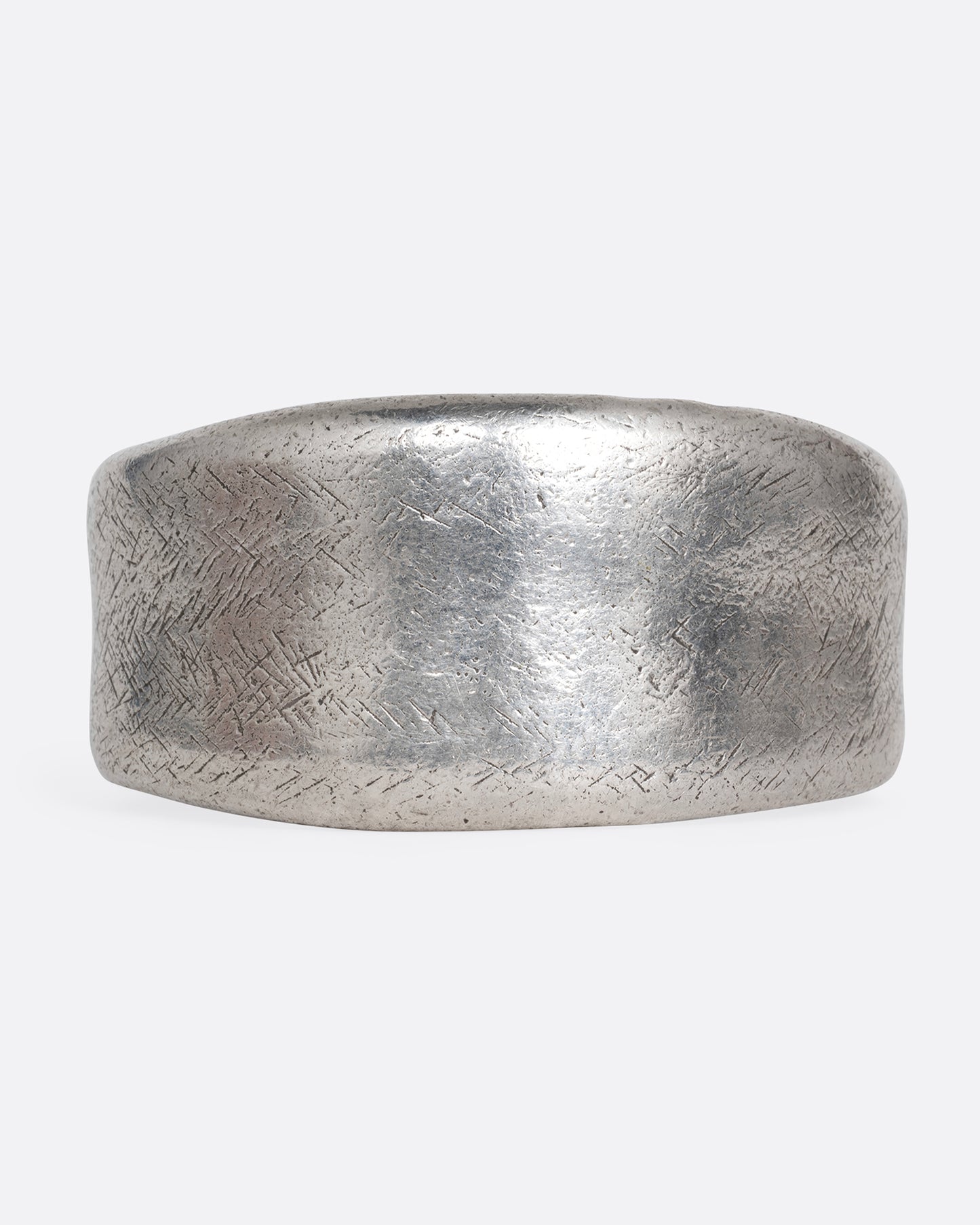 A silver cuff bracelet with a patinated finish and smooth edges. Shown from the front.