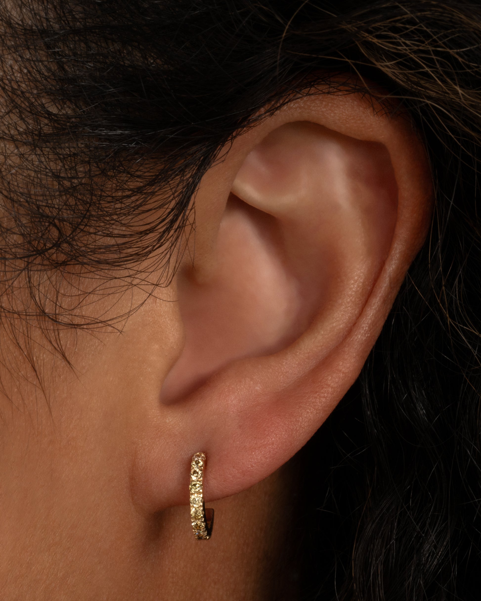 Small yellow gold hoops with green and brown pave diamonds. Shown worn in an ear.