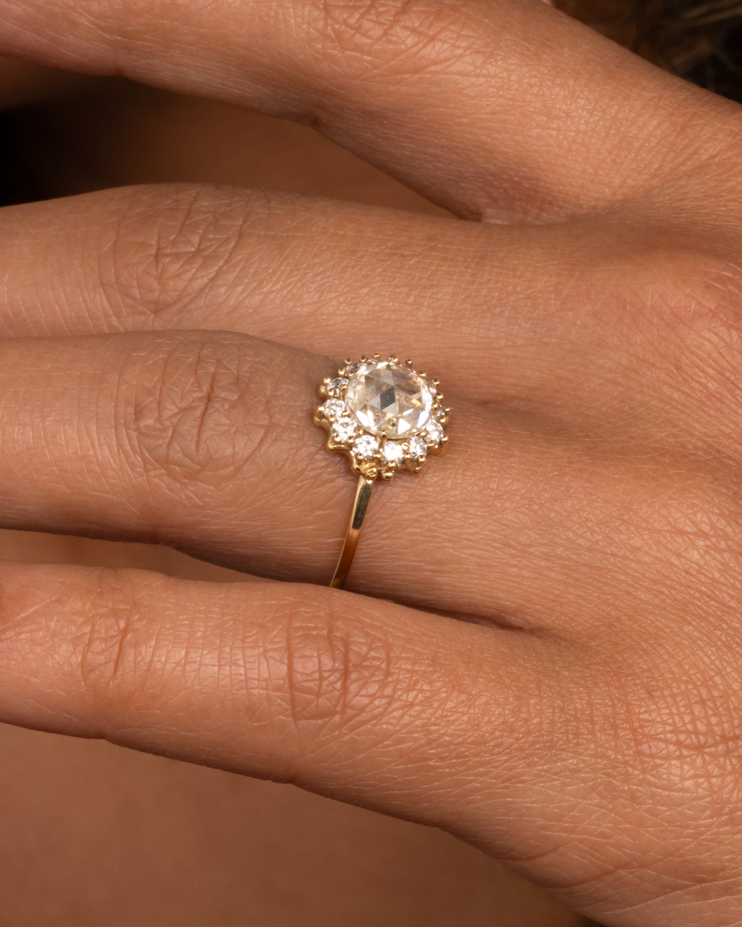 This light champagne, rose cut diamond is surrounded by a diamond halo, giving it the illusion of a shining sun. Shown worn on hand.