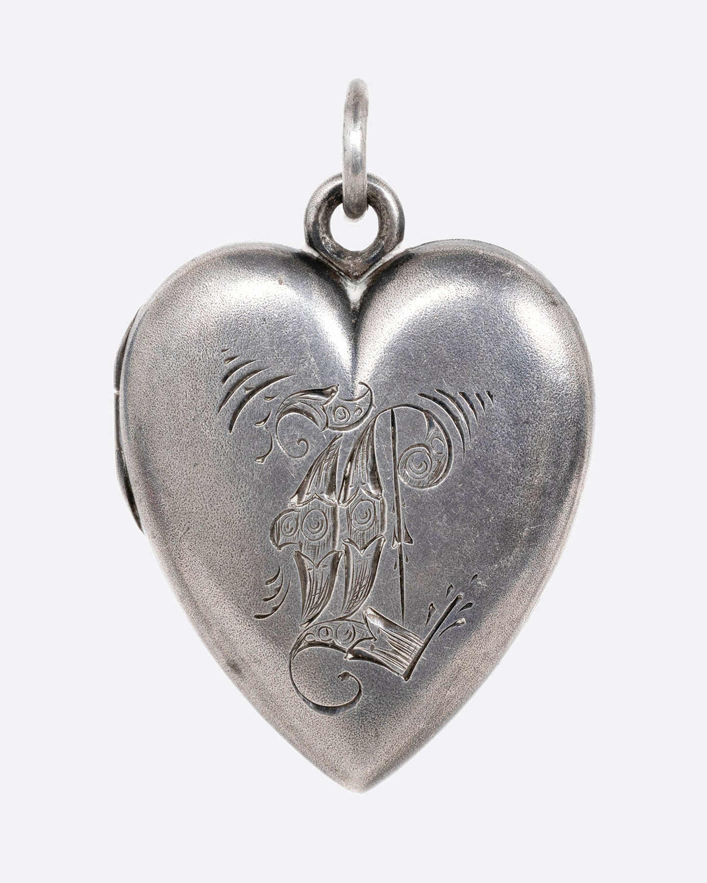 A silver heart shaped locket with an engraved 'L'. Shown from the front.