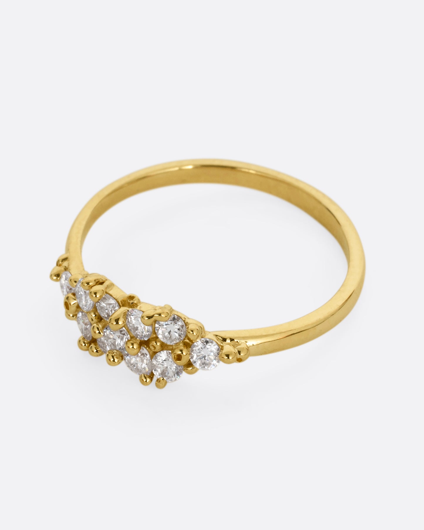 A yellow gold ring with a large cluster of diamonds and tiny gold droplets. Shown from the side.