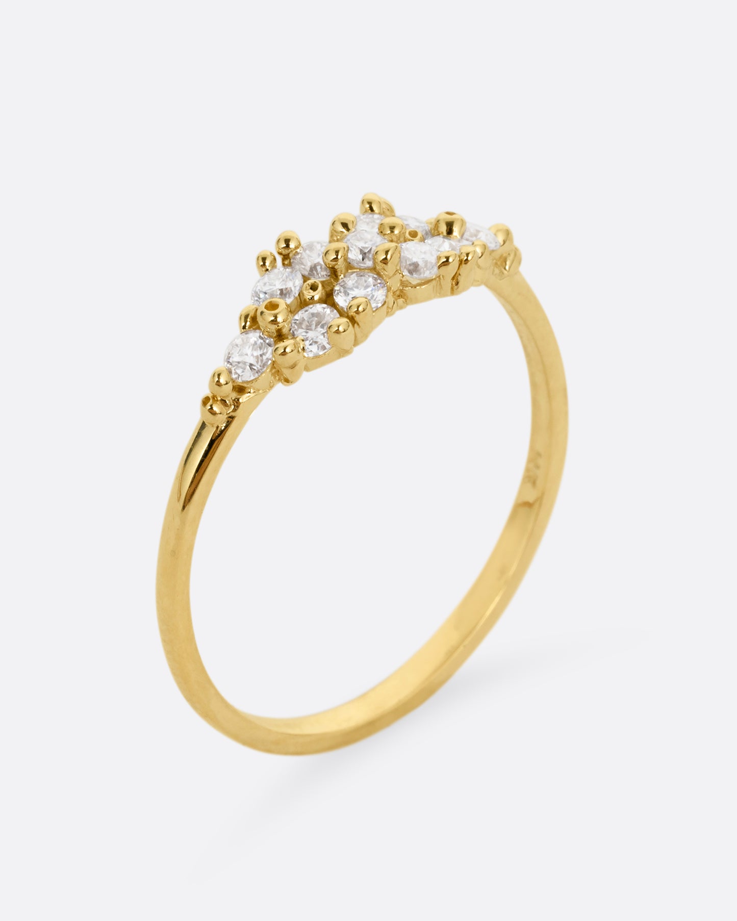 A yellow gold ring with a large cluster of diamonds and tiny gold droplets. Shown standing up from the side.