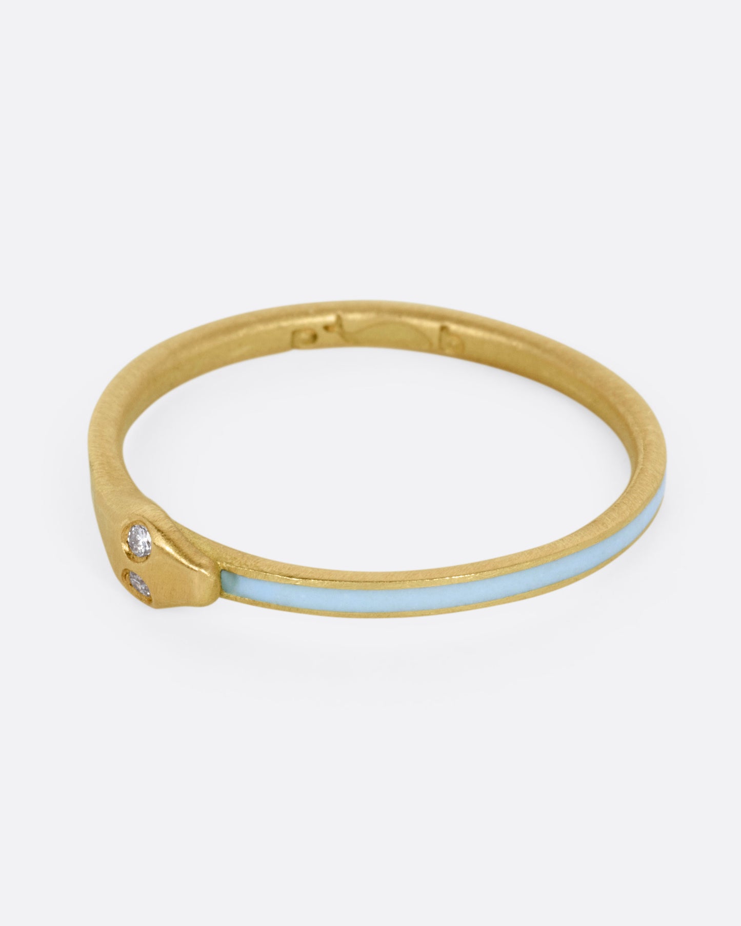 A yellow gold ouroboros ring with diamond eyes and light blue enamel, shown from the side.