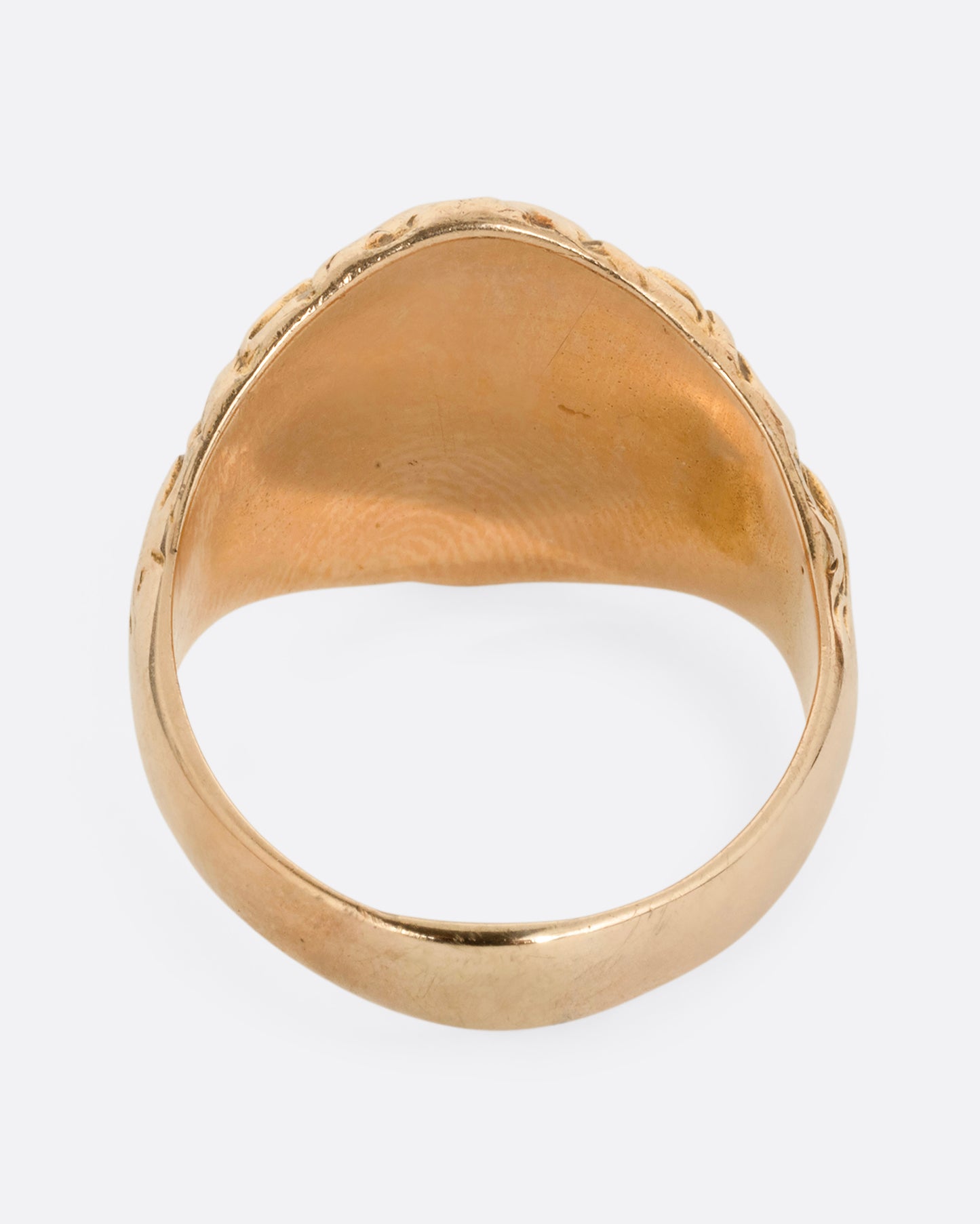 A yellow gold lion ring with ruby eyes and a single diamond in its mouth. Shown from the back.