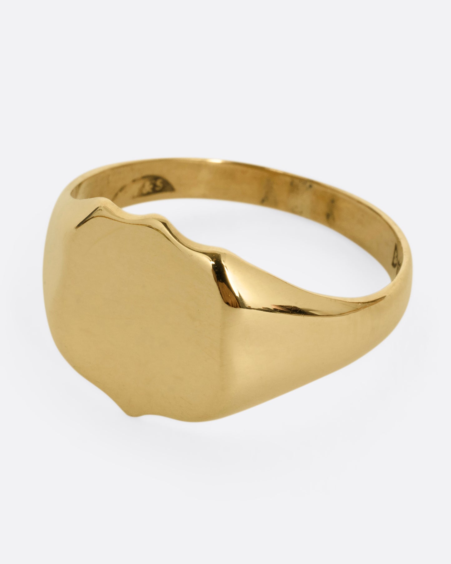 A yellow gold shield shaped signet ring. Shown from the side.