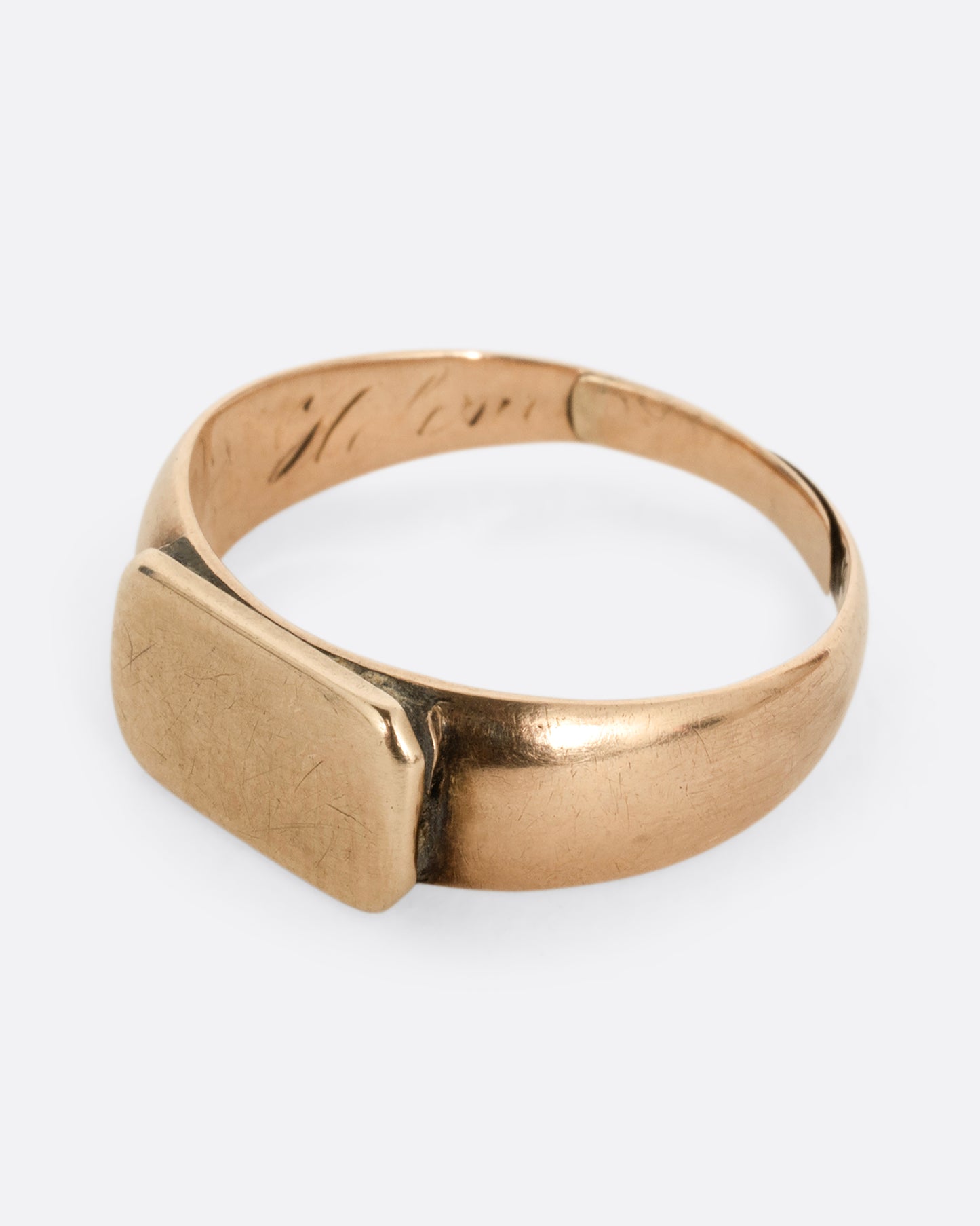 A yellow gold signet ring with a rectangular face. Shown from the side.